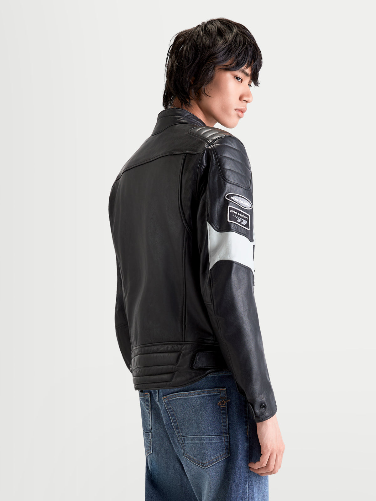 Alpinestars Revern Kurtka skórzana męska miejska motocyklowa w kolorze czarnym i szarym metalicznym, widok z tyłu na modelu prezentującym postarzaną skórę licową z motywami wyścigowymi i konstrukcją gotową na protektory