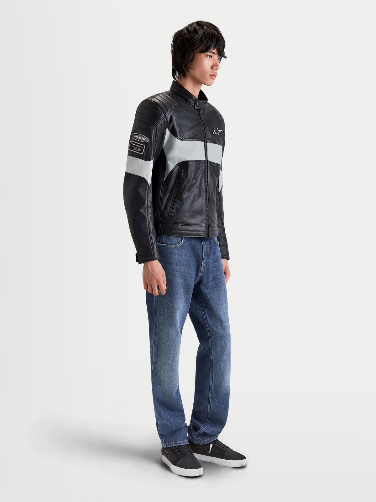 Alpinestars Revern Kurtka skórzana męska, miejska motocyklowa kurtka skórzana w kolorze czarnym i szarym metalicznym, widok z boku w ujęciu na modelu w jeansach, wykonana z postarzanego miękkiego tybetu o klasycznym designie
