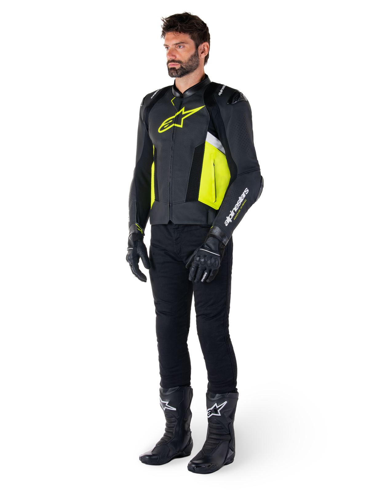 Model ubrany w skórzaną kurtkę Alpinestars Missile V3 Airflow w kolorze czarnym, żółtym fluo i białym, zestawioną z czarnymi rękawicami, spodniami i butami motocyklowymi, prezentujący perforowaną skórzaną konstrukcję i estetykę inspirowaną wyścigami.