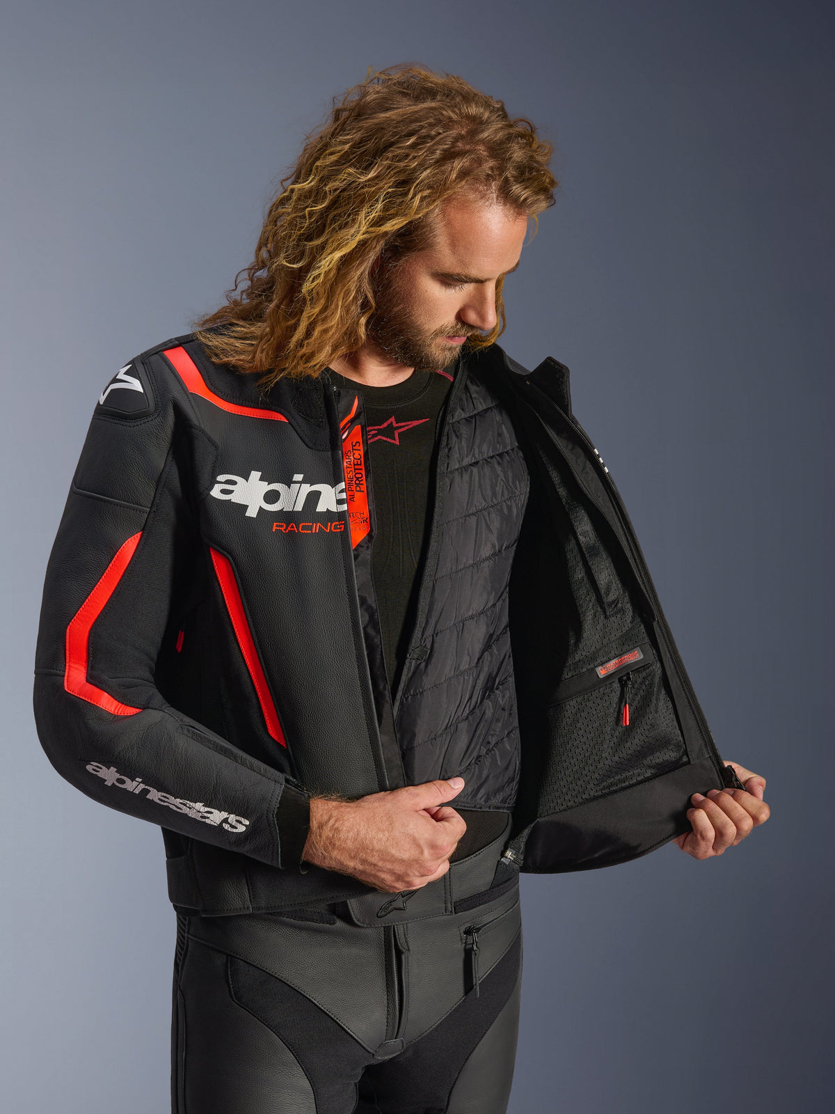 Alpinestars GP Force V2 Leather Jacket, czarno-czerwona fluo, szczegółowy widok wnętrza na modelu prezentujący wypinaną kamizelkę termiczną i wodoodporną kieszeń wewnętrzną, konstrukcja z wysokiej jakości skóry dla ochrony sportowej