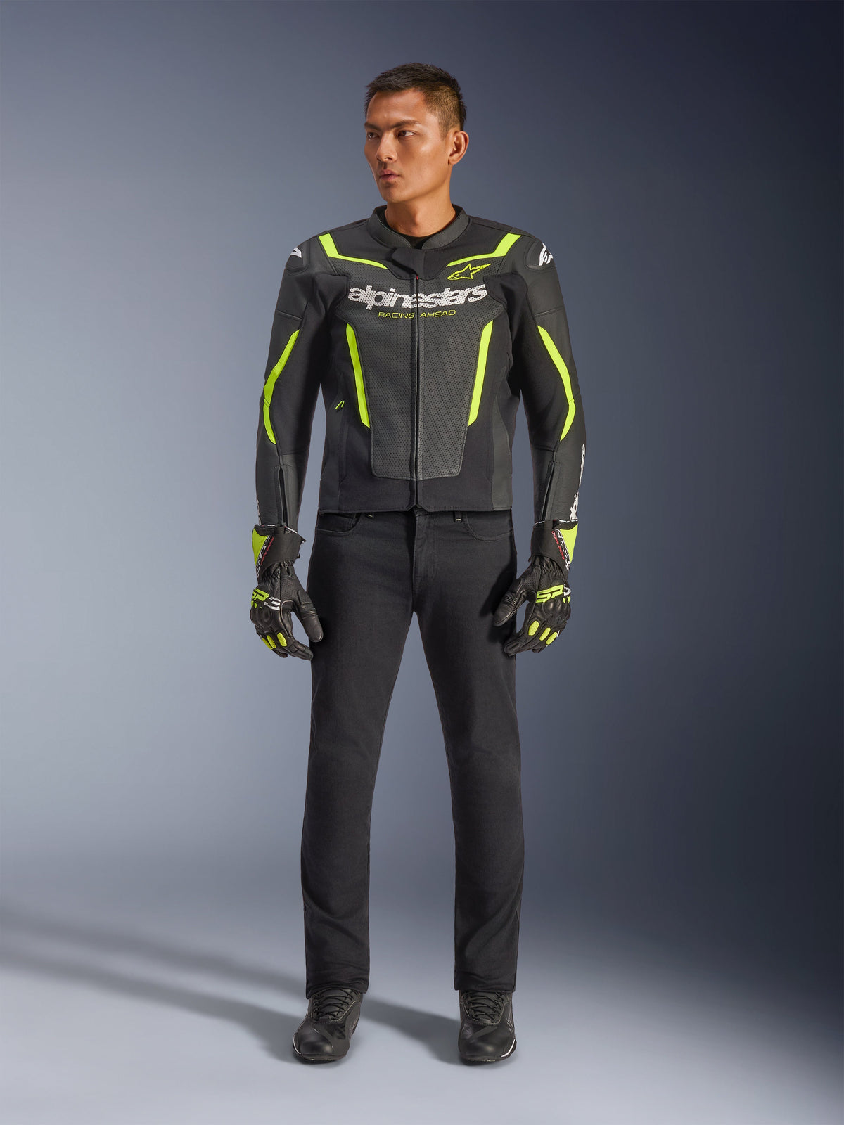 Alpinestars GP Force V2 Air Leather Jacket, czarno-żółta fluo, perforowana skórzana kurtka sportowa z wyraźnymi żółtymi akcentami i logo Alpinestars, noszona z czarnymi spodniami i dopasowanymi rękawicami motocyklowymi
