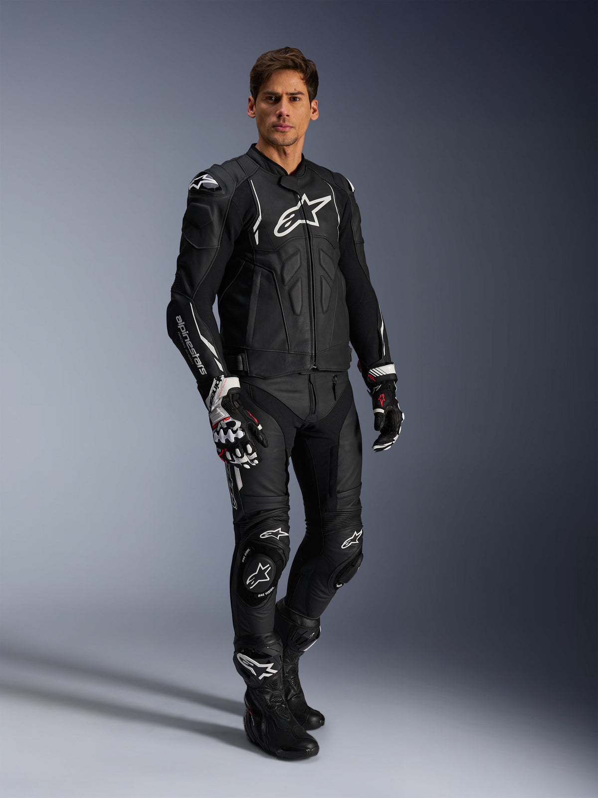 Spodnie skórzane Alpinestars Missile V3 i dopasowana czarna kurtka skórzana, pełny kombinezon motocyklowy, czarny z białym brandingiem Alpinestars na klatce piersiowej i kolanach, zawiera profesjonalne rękawice i buty wyścigowe, stylowa odzież ochronna na drogę i tor.