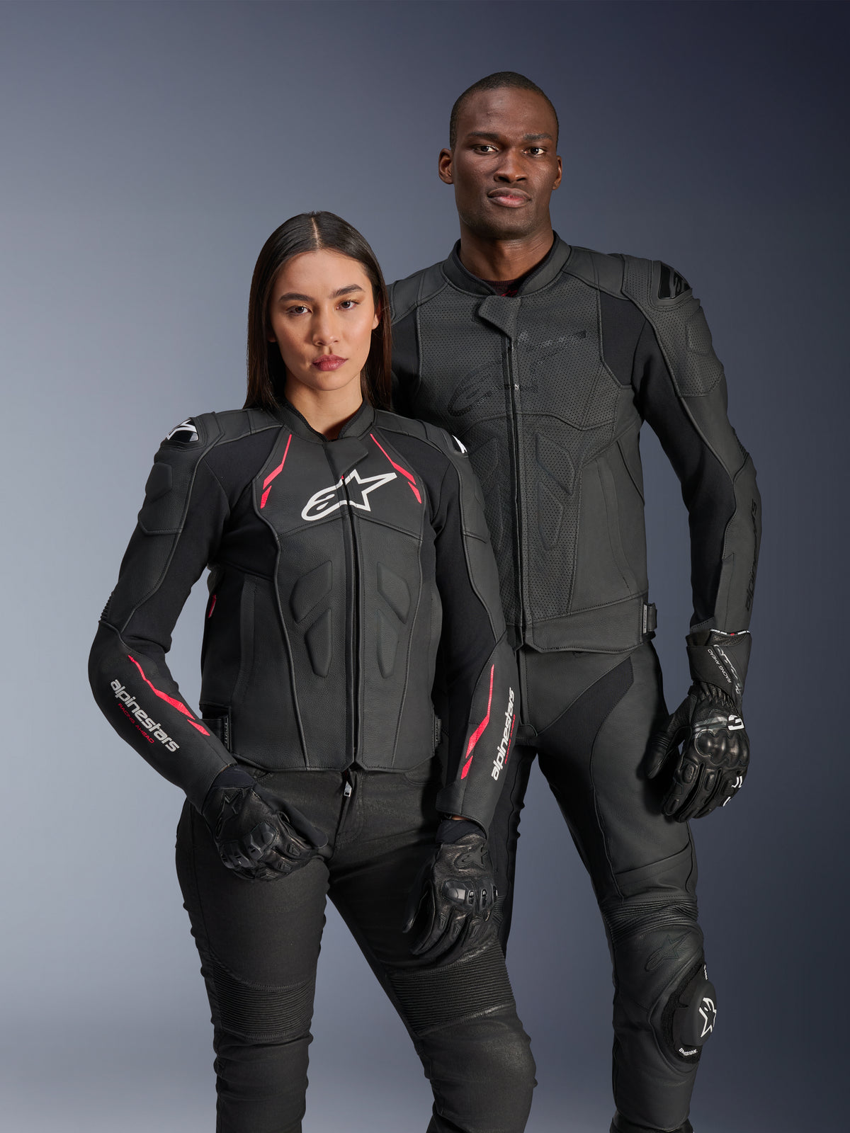 Alpinestars Dusk Airflow and Stella Dusk Leather Jackets, male and female riders wearing black leather motorcycle jackets, men's jacket featuring perforated leather for ventilation, women's jacket with red accents and white logos, coordinated with black riding pants and gloves, performance sport riding apparel