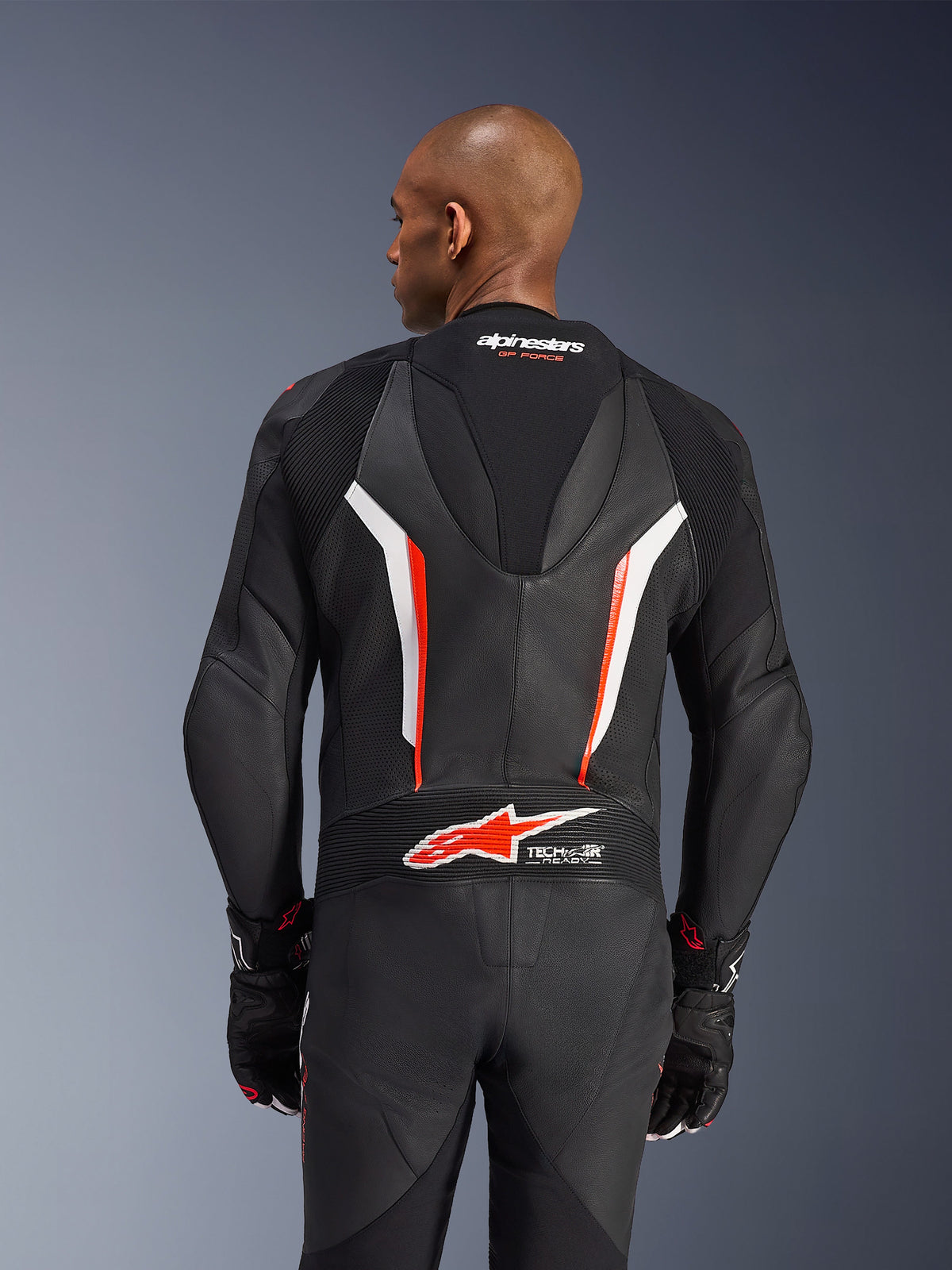 Alpinestars GP Force V2 Leather Suit, 1-Piece Motorcycle Suit, Black White and Red Fluo, back view of upper body showing perforated leather and Tech-Air Ready logo, worn with matching black and red gloves