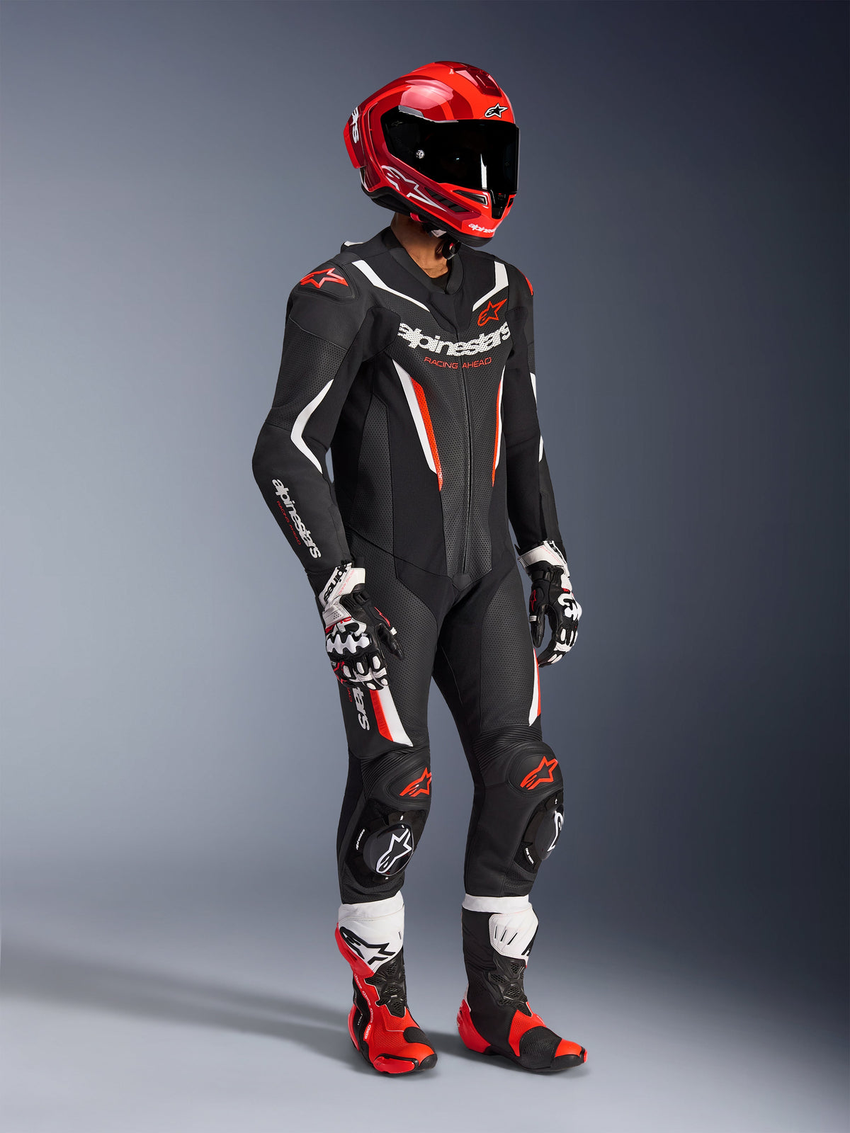 Alpinestars GP Force V2 Leather Suit - 1Piece, professional racing suit in Black White and Red Fluo, featuring perforated leather panels and DFS Lite shields. Complete track setup with red racing helmet, matching gloves, and boots.
