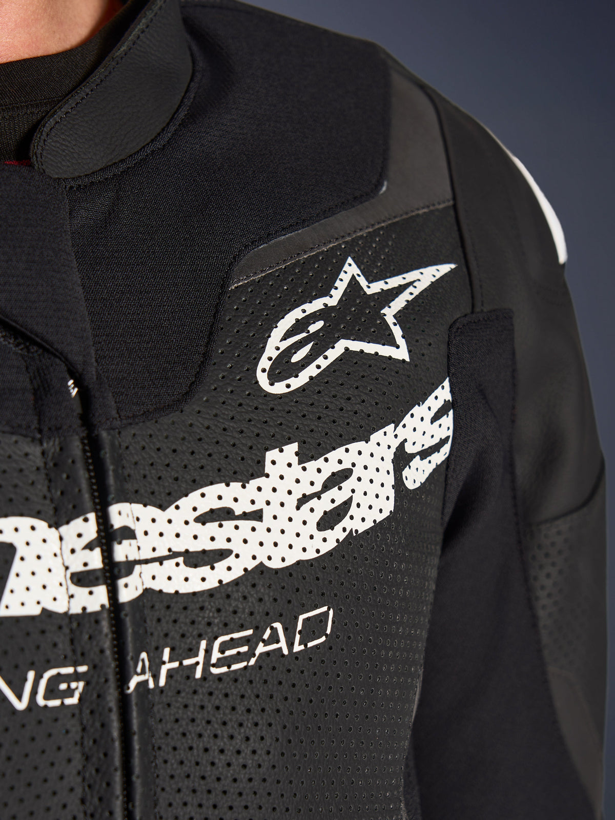 Alpinestars GP Force V2 2-Piece Leather Suit, Racing/Sport Motorcycle Suit, Black, close-up of perforated leather chest with white Alpinestars logo and branding, highlighting ventilation holes and textured construction.