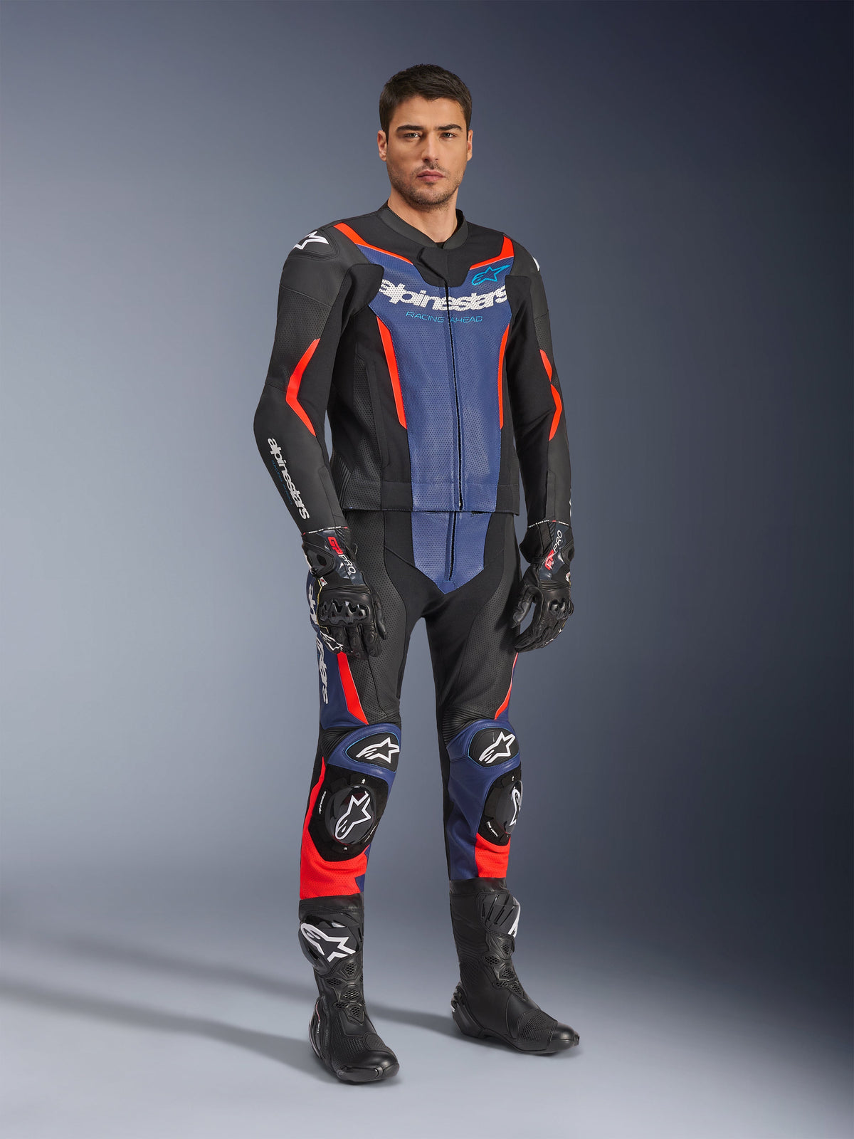 Alpinestars GP Force V2 Leather Suit 2-Piece, Motorcycle Leather Suit, Black Blue and Red Fluo, worn with matching black racing gloves and boots, featuring perforated panels and protective sliders, aerodynamic design for sport riding