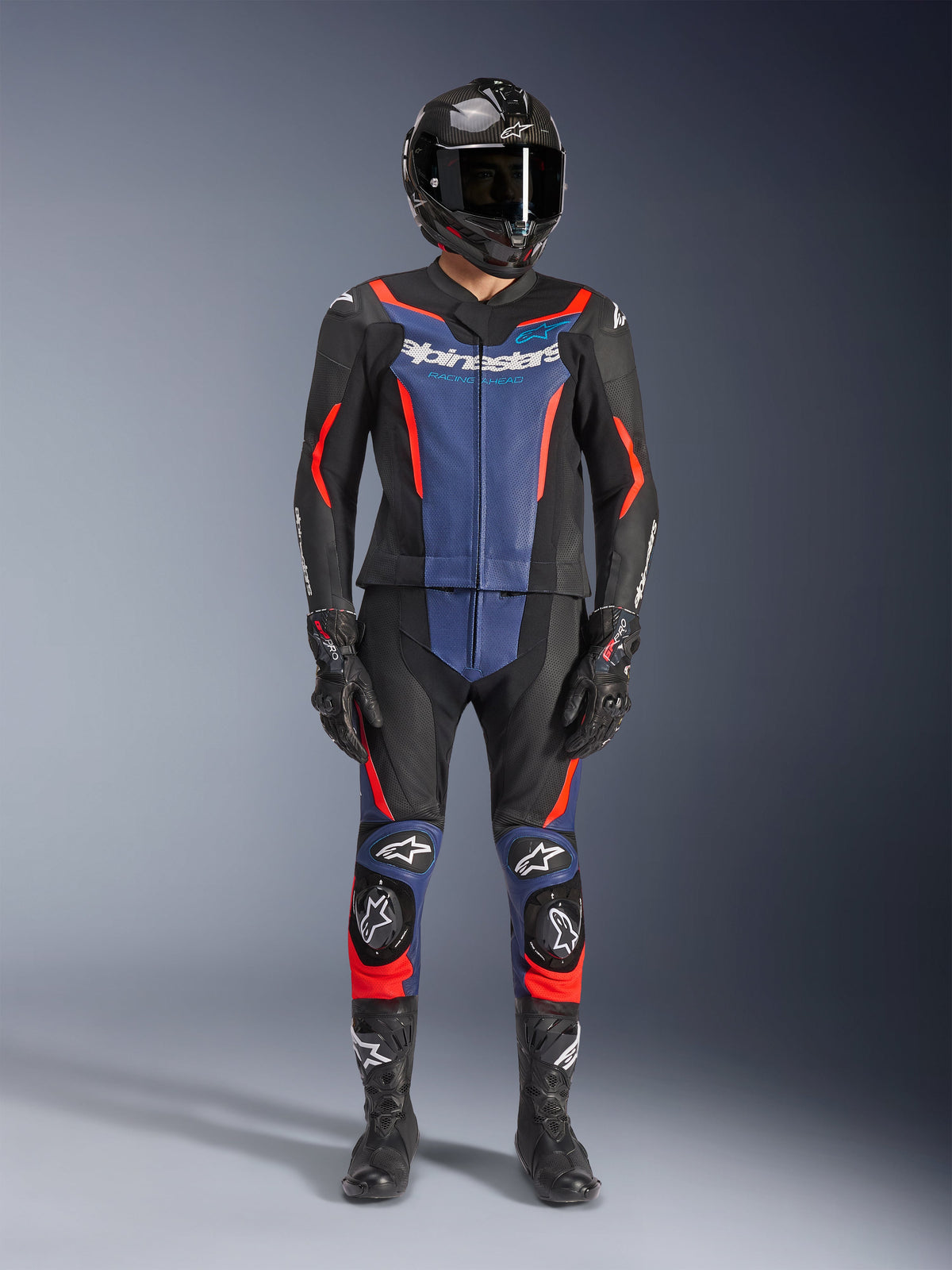 Alpinestars GP Force V2 Leather Suit- 2Piece, Black Blue and Red Fluo, worn with a carbon-fiber full-face helmet, black racing gloves, and boots, featuring blue chest panels and red fluorescent accents, professional motorcycle racing gear