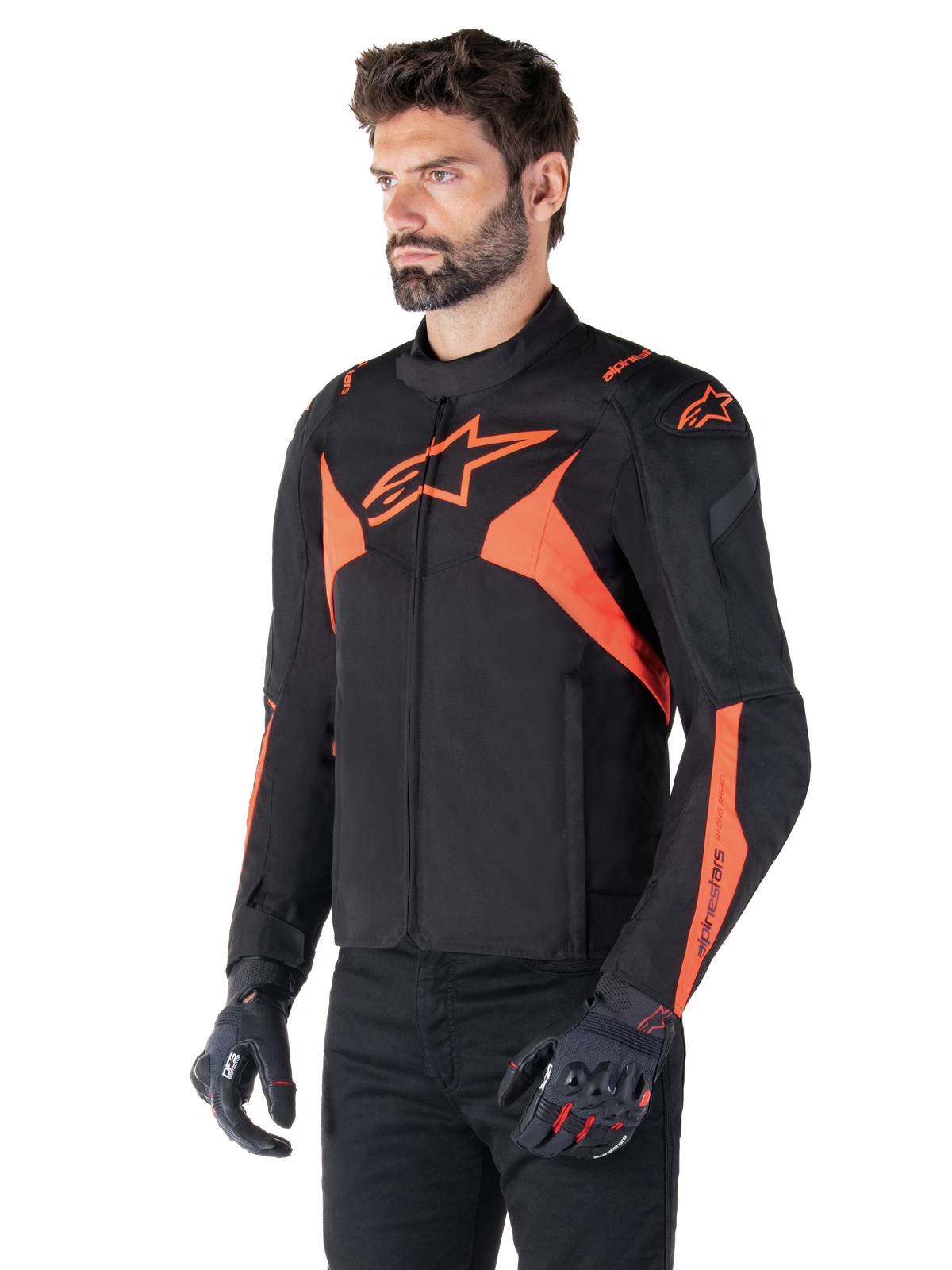 Alpinestars T-Jaws V4 Waterproof Jacket, sportowa kurtka motocyklowa, czarna z elementami Red Fluo, prezentowana na modelu, wyraźne pomarańczowe logo gwiazdy na klatce piersiowej i ramionach, czarne rękawice i spodnie