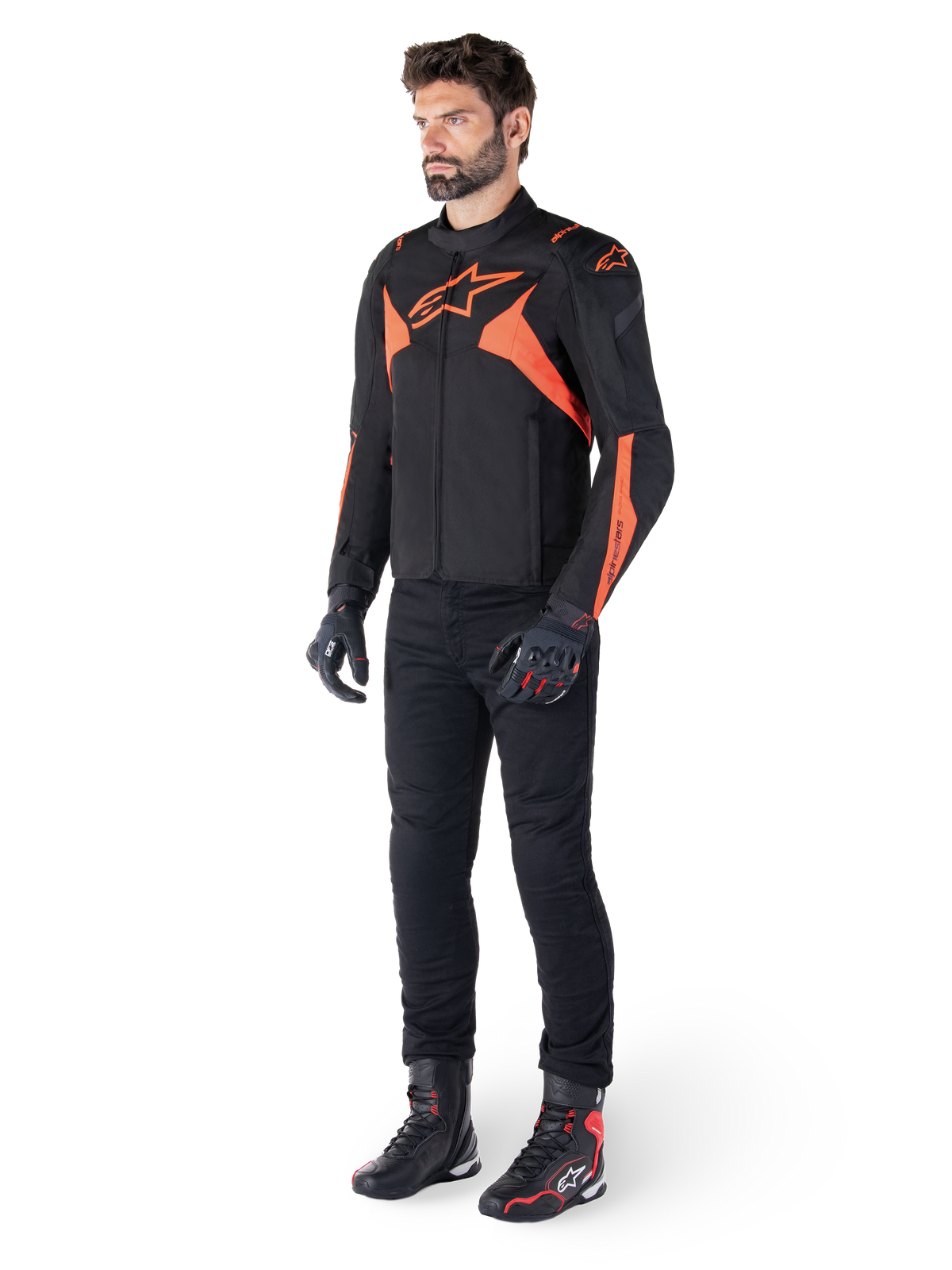 Alpinestars T-Jaws V4 Waterproof Jacket, czarna i czerwona fluo, noszona przez modela w czarnych spodniach, rękawicach i butach, z jasnopomarańczowymi akcentami i logo Alpinestars, sportowy design do jazdy motocyklem