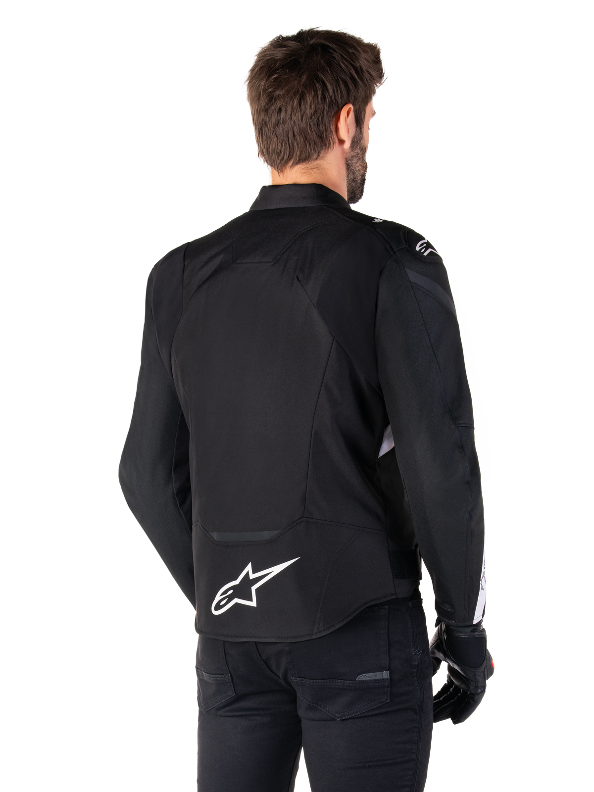 Alpinestars T-Jaws V4 Waterproof Jacket, czarno-biała, widok z tyłu, sportowa tekstylna kurtka motocyklowa z białym logo w dolnej części pleców, noszona z czarnymi rękawicami i spodniami, o ulepszonym sportowym kroju