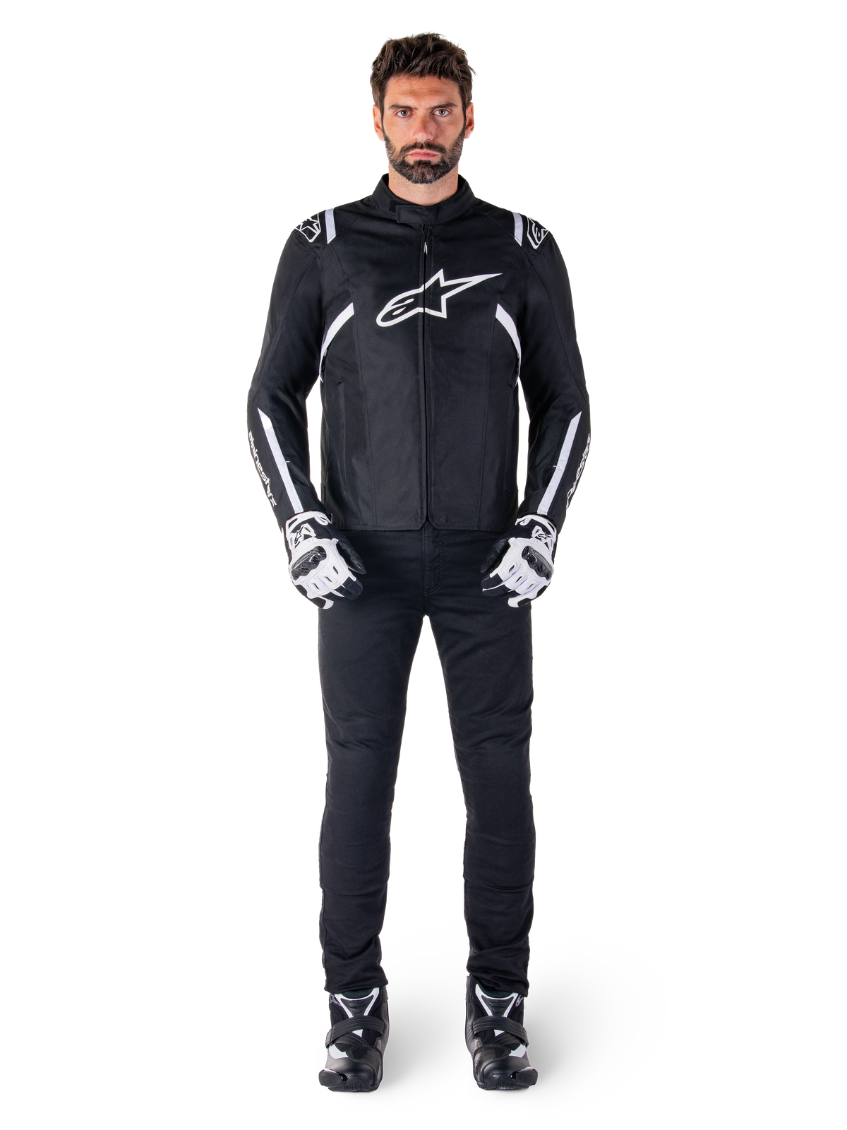 Alpinestars T-SPS V2 Waterproof Jacket, czarno-biała, noszona przez modela z czarnymi spodniami i dopasowanymi rękawicami, białe logo Alpinestars na klatce piersiowej i akcenty na rękawach, sportowy krój do jazdy motocyklowej w każdych warunkach pogodowych