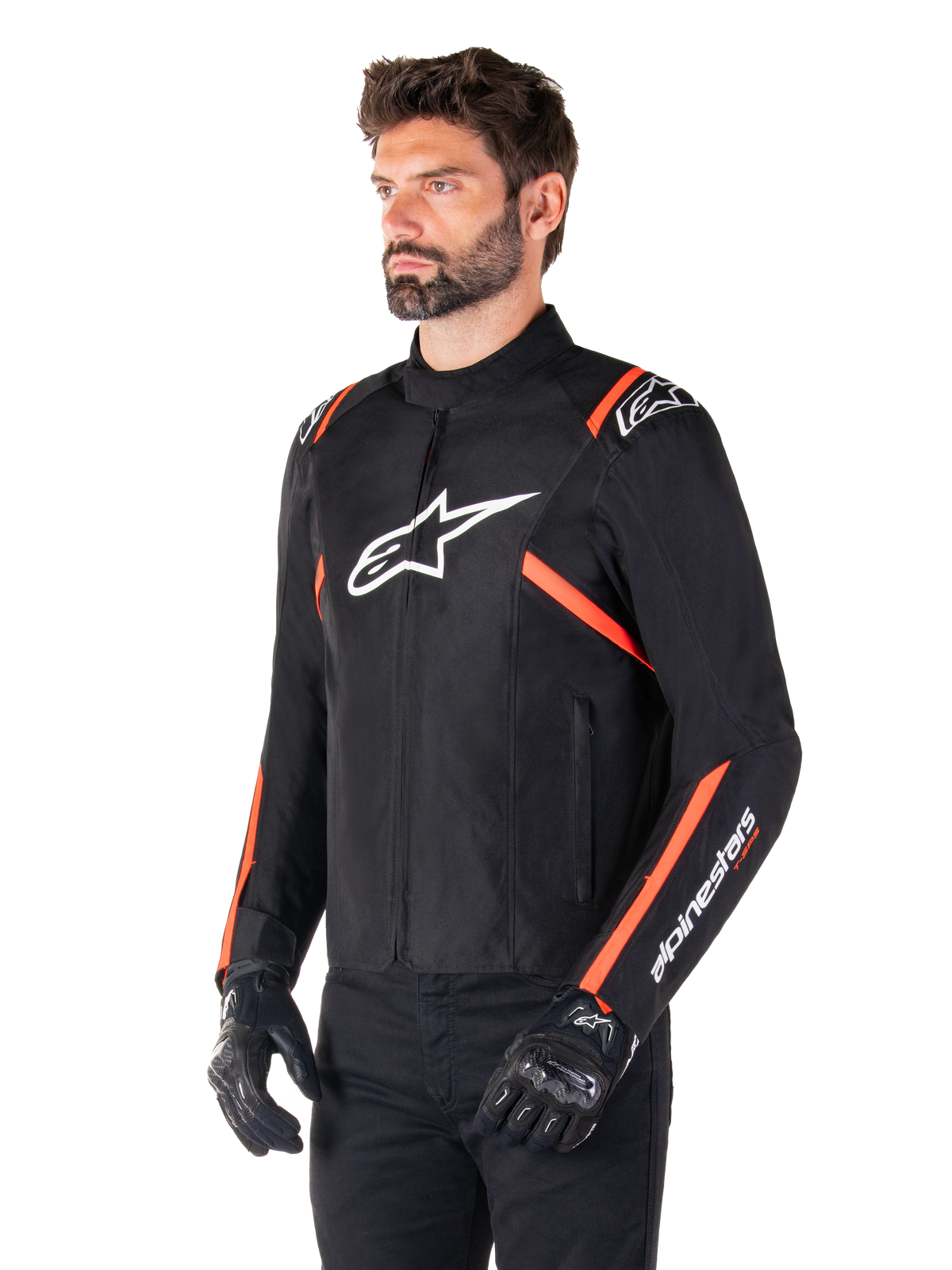 Alpinestars T-SPS V2 Waterproof Jacket, czarno-biała z fluorescencyjną czerwienią, noszona przez męskiego modela w czarnych rękawicach i spodniach, białe logo Alpinestars na klatce piersiowej, fluorescencyjne czerwone akcenty na ramionach i rękawach, sportowy tekstylny design
