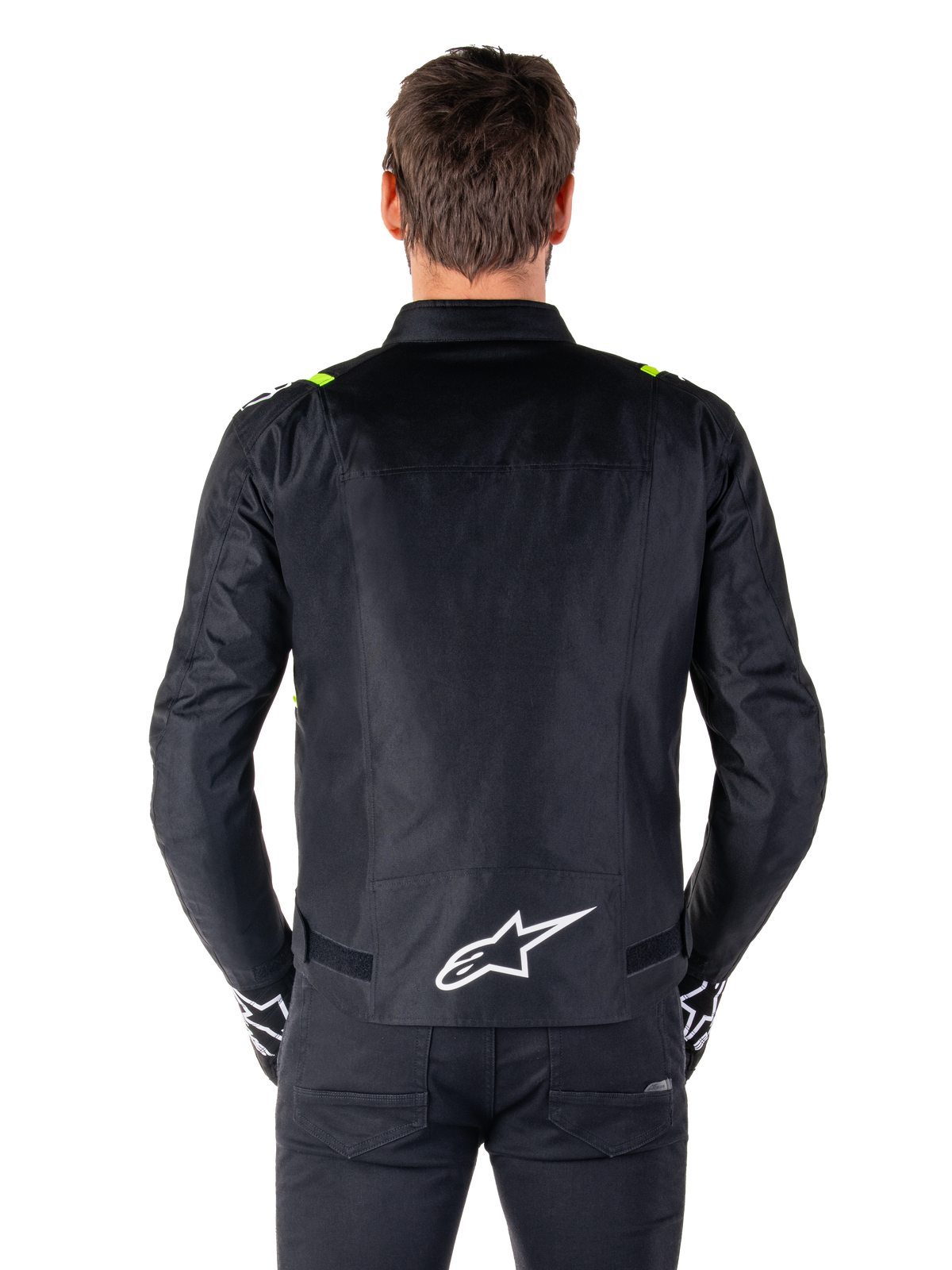 Wodoodporna kurtka Alpinestars T-SPS V2, widok z tyłu, czarna z żółtymi akcentami fluo na ramionach i białym logo gwiazdy na dole pleców, tekstylna kurtka motocyklowa o sportowej sylwetce, prezentowana na modelu
