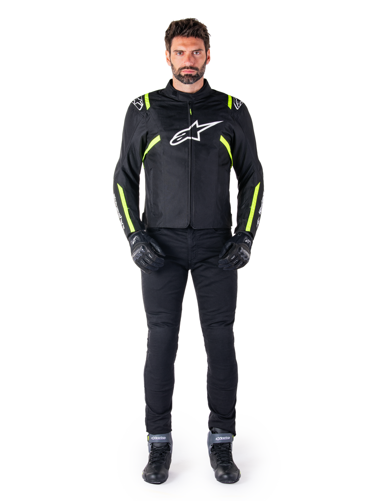 Alpinestars T-SPS V2 Waterproof Jacket, czarno-biało-żółta fluo, prezentowana przez modela w czarnych spodniach i rękawicach motocyklowych, białe logo Alpinestars na piersi, fluorescencyjne akcenty na ramionach i rękawach, sportowa odzież motocyklowa