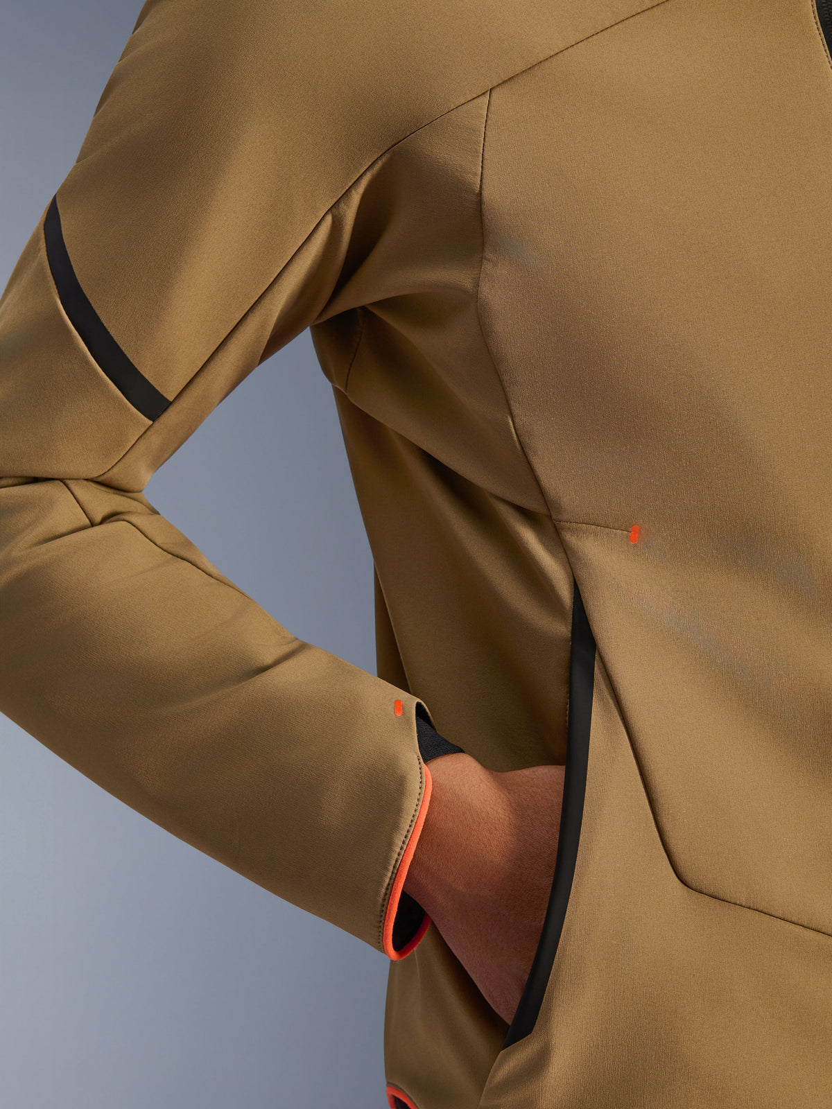 Zbliżenie na kurtkę Alpinestars Aeroshell Waterproof Jacket, ciemne khaki z czarnymi i pomarańczowymi akcentami fluo, detal ukrytej kieszeni na zamek i mankietu rękawa, elastyczny materiał softshell do jazdy motocyklem