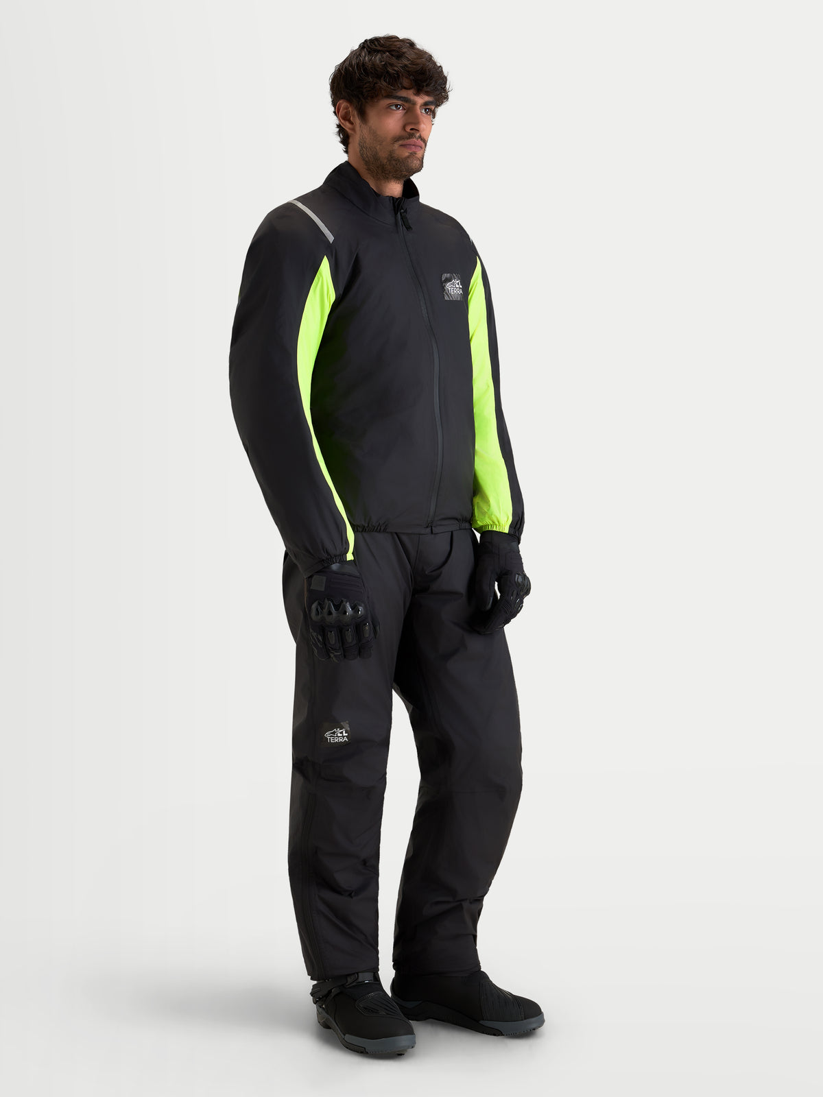 Alpinestars Harok V2 Drystar Gear Set, męski zestaw odzieży motocyklowej z wodoodporną kurtką i pasującymi spodniami w kolorze czarnym z panelami w odcieniu żółtym high-visibility i czarnymi rękawicami, pełny widok sylwetki na modelu