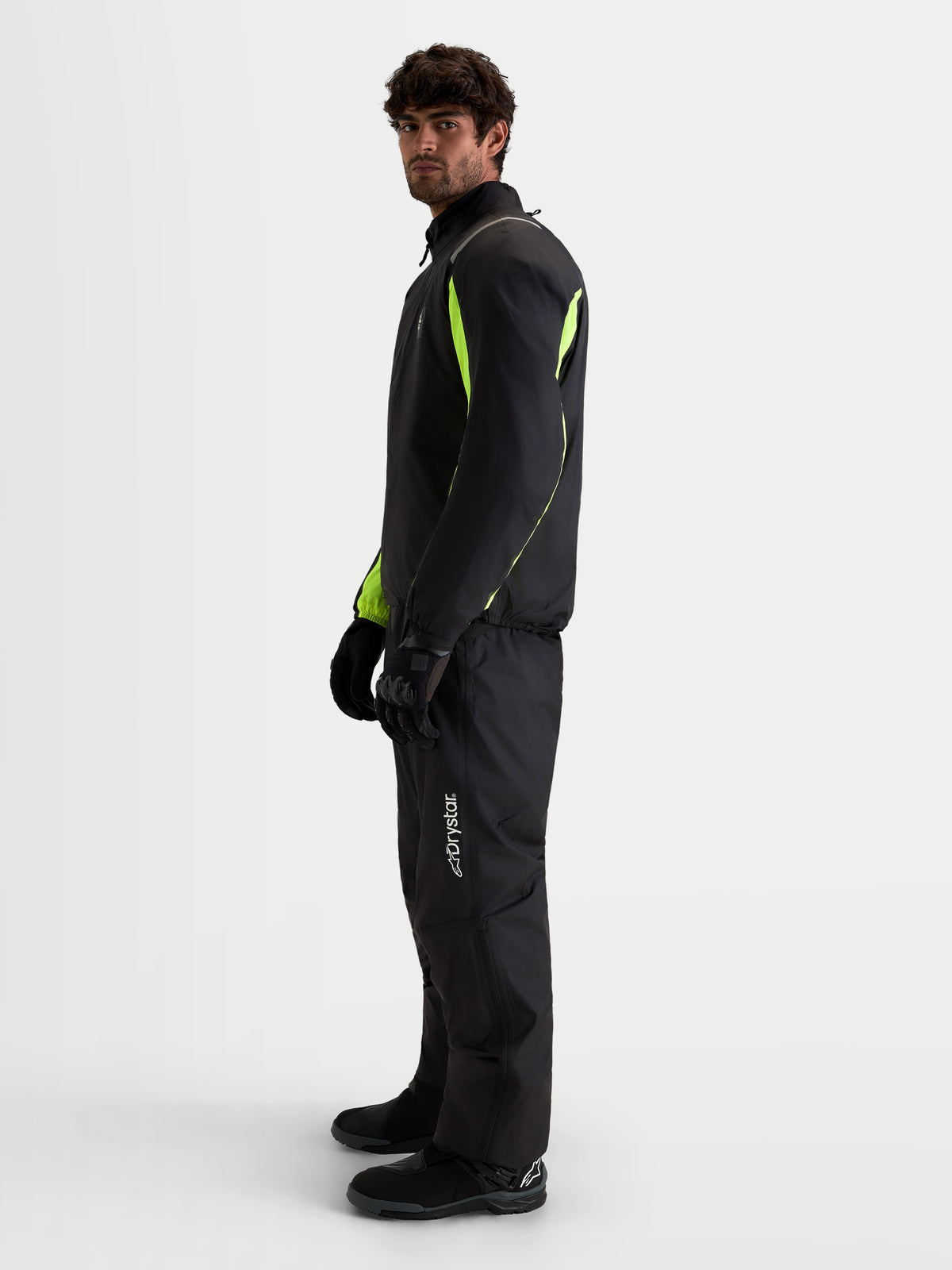 Alpinestars Harok V2 Drystar Gear Set, wodoodporna tekstylna kurtka i spodnie motocyklowe, czarne i żółte fluorescencyjne, widok z profilu na modelu w pasującym sprzęcie i rękawicach
