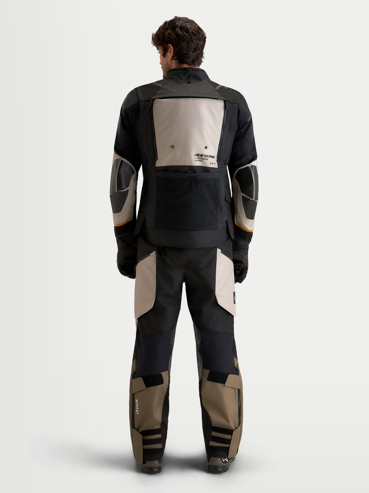 Alpinestars Harok V2 Drystar Gear Set, męski zestaw odzieży motocyklowej adventure w kolorze czarnym i khaki, widok z tyłu na modelu prezentującym wodoodporną odzież z wzmocnieniami ochronnymi