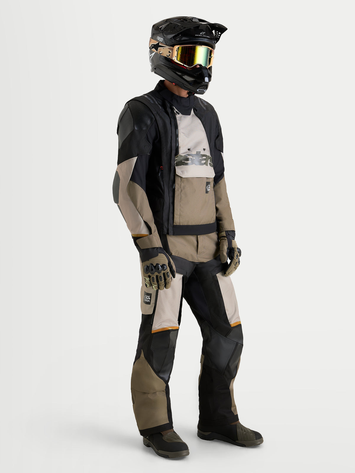 Alpinestars Harok V2 Drystar gear set, kurtka i spodnie motocyklowe adventure w kolorze czarnym i khaki, na modelu z pasującym kaskiem i goglami, prezentujące wodoodporną konstrukcję tekstylną na każdą pogodę