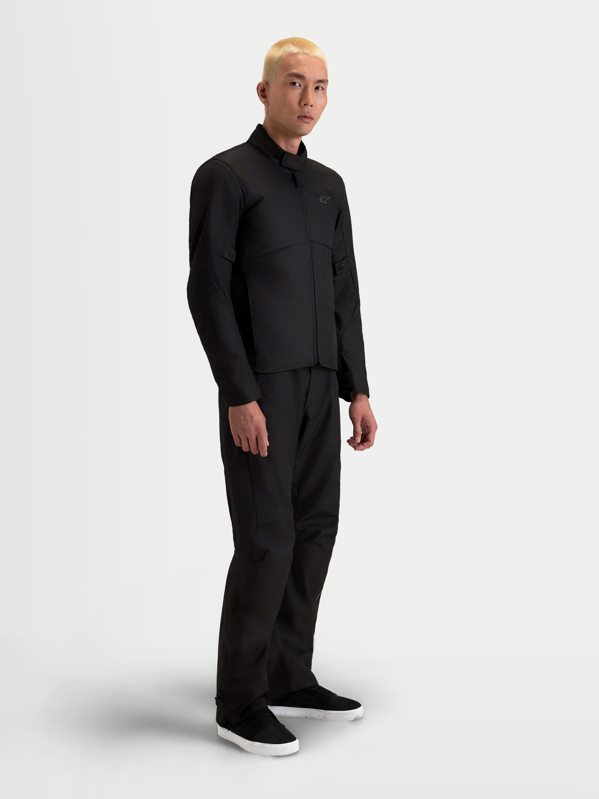 Alpinestars C-1 Waterproof Kurtka, męska miejska współczesna kurtka motocyklowa z materiału tekstylnego w kolorze czarnym, widok z boku na modelu w pasujących spodniach, o konstrukcji z wodoodpornego polimateriału i z kołnierzem o miękkim wykończeniu