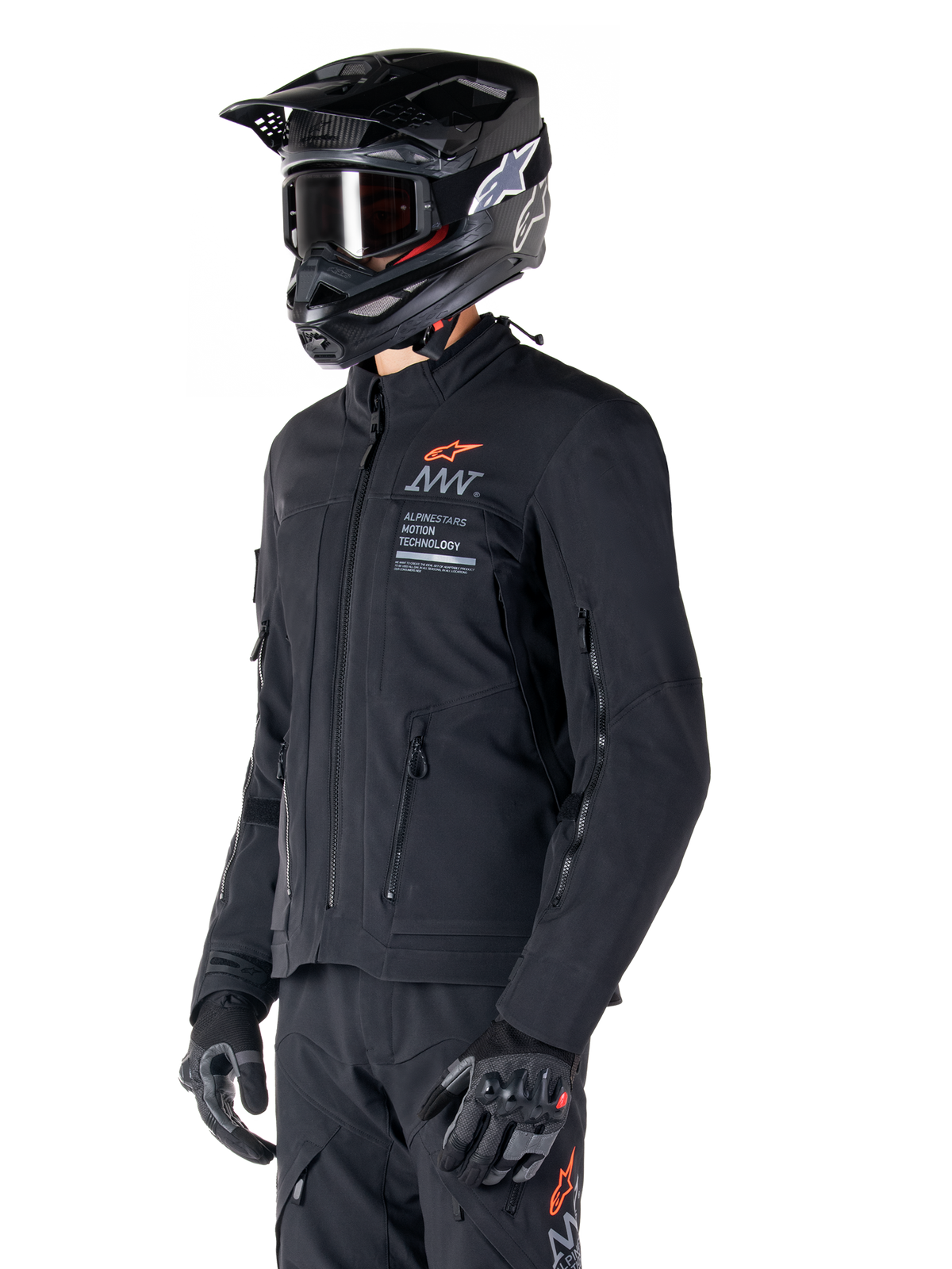 Kurtka Alpinestars AMT-8 Stretch Drystar® XF, czarna, noszona przez motocyklistę z dopasowanymi spodniami adventure i rękawicami, czarny kask motocrossowy i gogle, zapinane na zamek otwory wentylacyjne na klatce piersiowej i rękawach, branding Alpinestars Motion Technology z pomarańczowym logo, wysokiej jakości odzież adventure-touring