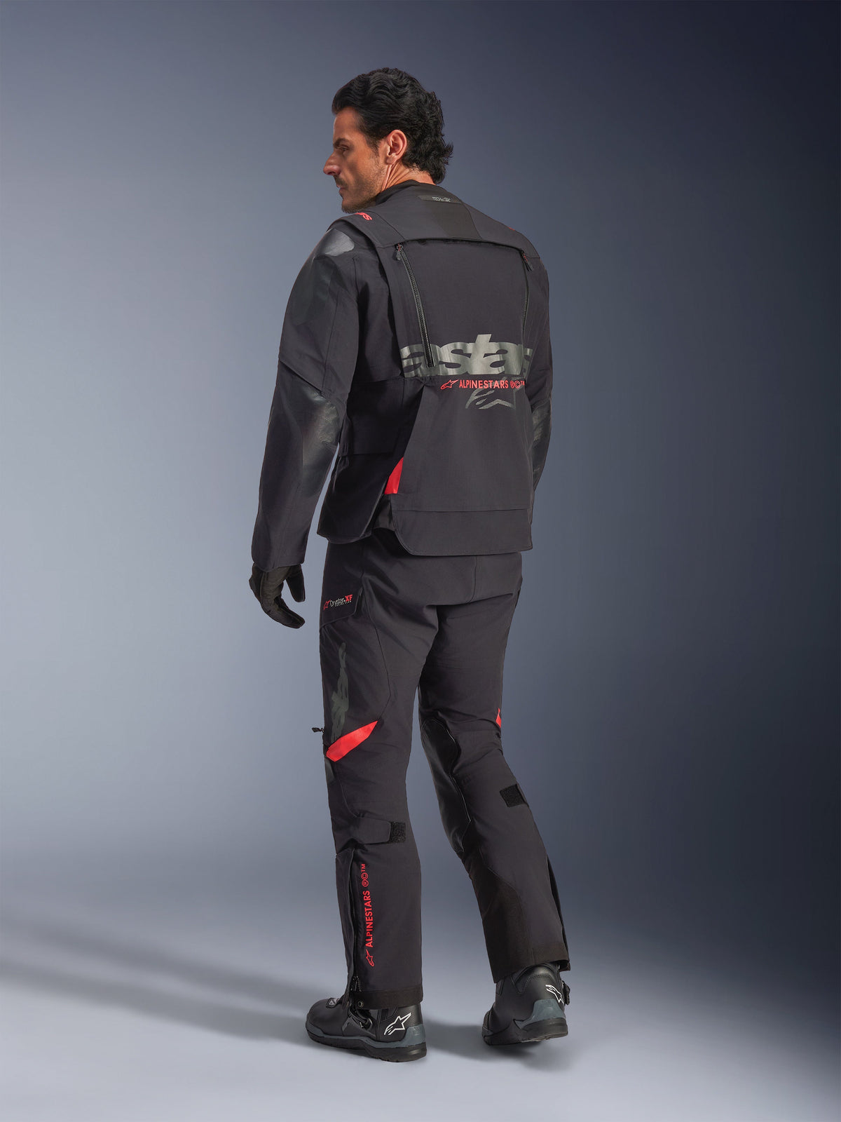Alpinestars Halo Pro Drystar® XF Laminated Jacket, motocyklowa kurtka przygodowa, w kolorze Black Dark Shadow z czerwonymi akcentami, widok z tyłu w zestawie z pasującymi spodniami i butami, szary branding na plecach, modułowa konstrukcja tekstylna do turystyki przygodowej