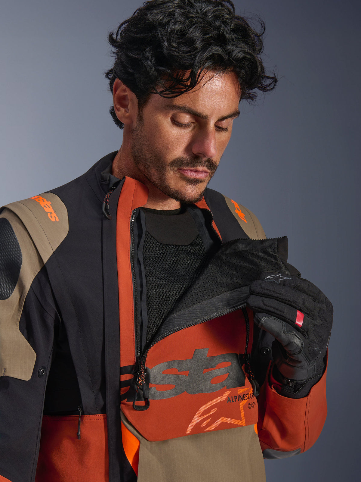 Laminowana kurtka Alpinestars Halo Pro Drystar® XF, kolorystyka Walnut Rust Black, męski model prezentujący modułowy system wentylacji poprzez rozpięcie przedniego panelu na klatce piersiowej i odsłonięcie czarnej siatki, techniczna kurtka motocyklowa adventure z rdzawymi i beżowymi akcentami.