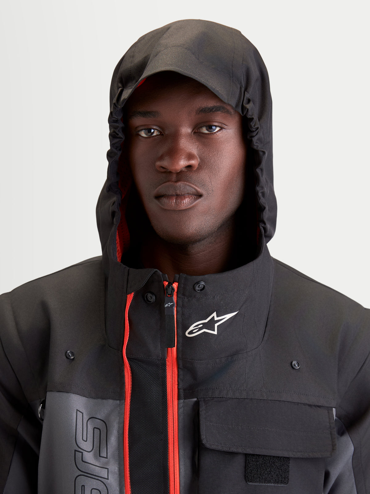 Alpinestars Morfex Parka WP kurtka motoryzacyjna męska miejska w kolorze szarym i czarnym, zbliżenie na modela w kurtce z założonym zintegrowanym kapturem i widocznymi czerwonymi akcentami we wnętrzu