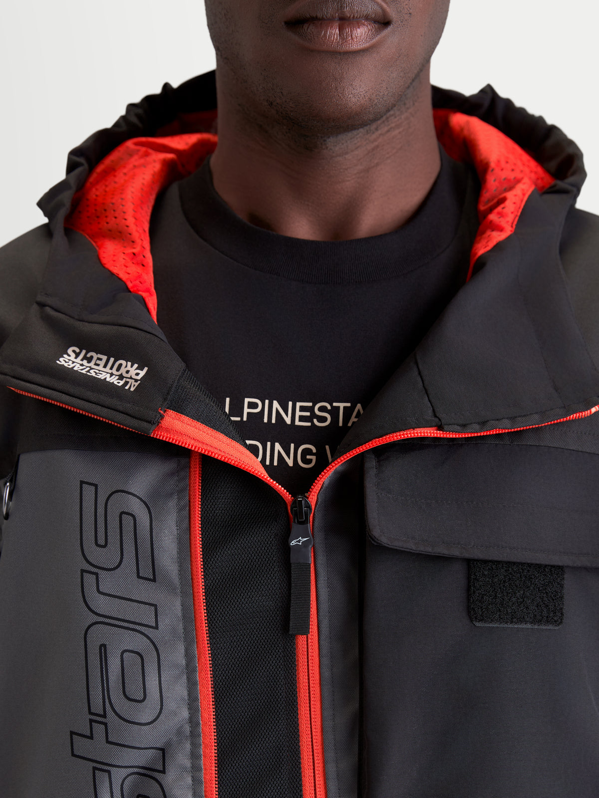 Alpinestars Morfex Parka Wp Kurtka, męska miejska kurtka motocyklowa w kolorze szarym i czarnym, zbliżenie przedstawiające zintegrowany kaptur, czerwoną wyściółkę wewnętrzną i detale kieszeni na piersi