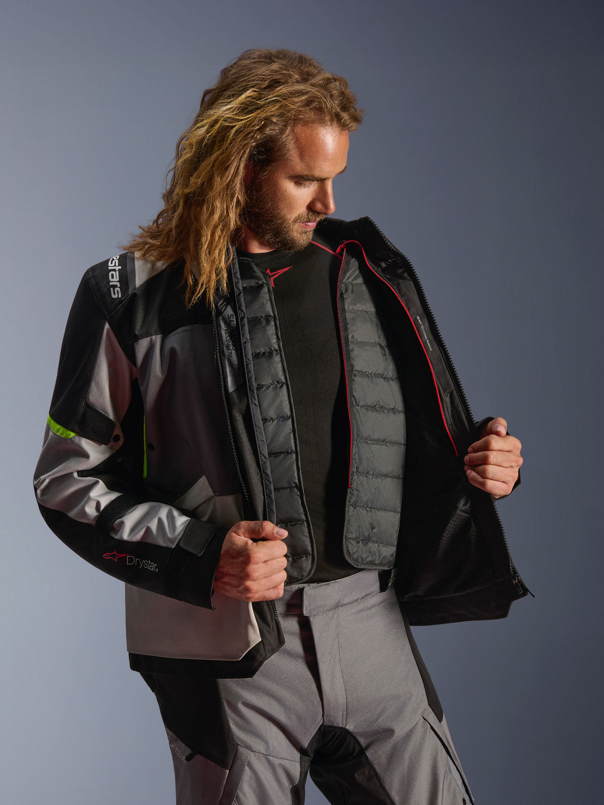 Kurtka Alpinestars Andes V4 Drystar®, odzież motocyklowa adventure w kolorach Dark Gray, Ice Gray i Yellow Fluo, męski model prezentujący wewnętrzną pikowaną podpinkę ocieplającą, noszona z pasującymi spodniami motocyklowymi, konstrukcja na każdą pogodę