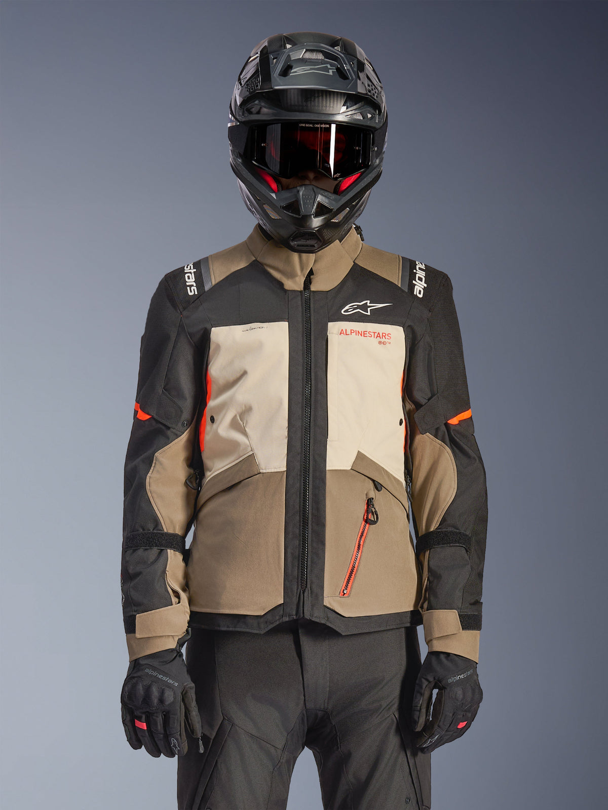 Kurtka Alpinestars Andes V4 Drystar®, Walnut Mastic Black, kurtka adventure touring z panelami w kolorze orzechowego brązu i kremowego mastyksu, czarne rękawy i jaskrawopomarańczowe akcenty, czarny kask motocyklowy, ciemne gogle i czarne rękawice