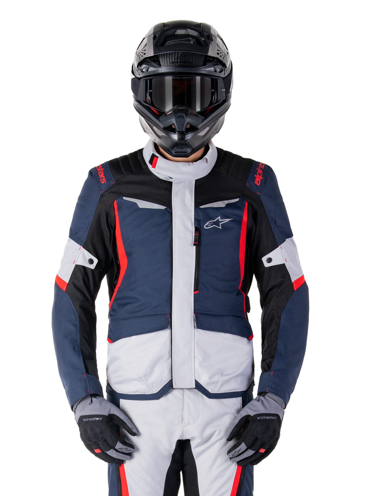 Kurtka Alpinestars ST-1 Waterproof, kurtka adventure touring, ciemnoniebieska, czarna i jaskrawoczerwona, noszona z czarnym kaskiem adventure i szarymi rękawicami, jasnoszare panele i czerwone akcenty na ramionach i zamkach, smukły design z logo Alpinestars na piersi, wytrzymała wodoodporna odzież do jazdy na motocyklu
