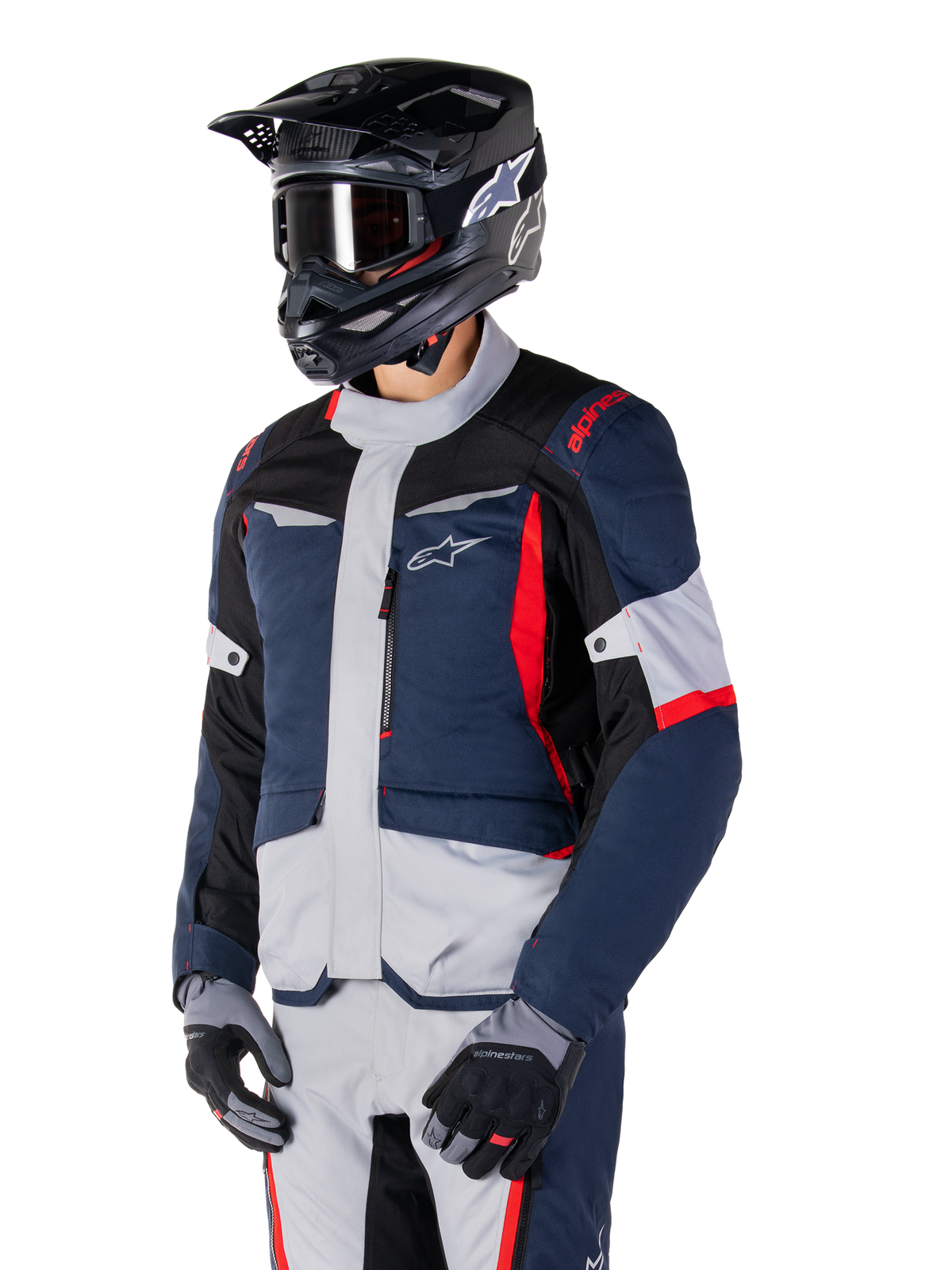 Alpinestars ST-1 Waterproof Jacket, motocyklowa kurtka adventure touring w kolorach ciemnoniebieskim, czarnym i jaskrawoczerwonym, noszona z czarnym kaskiem i szarymi rękawicami, o nowoczesnym designie z funkcjonalnymi kieszeniami i brandingiem Alpinestars