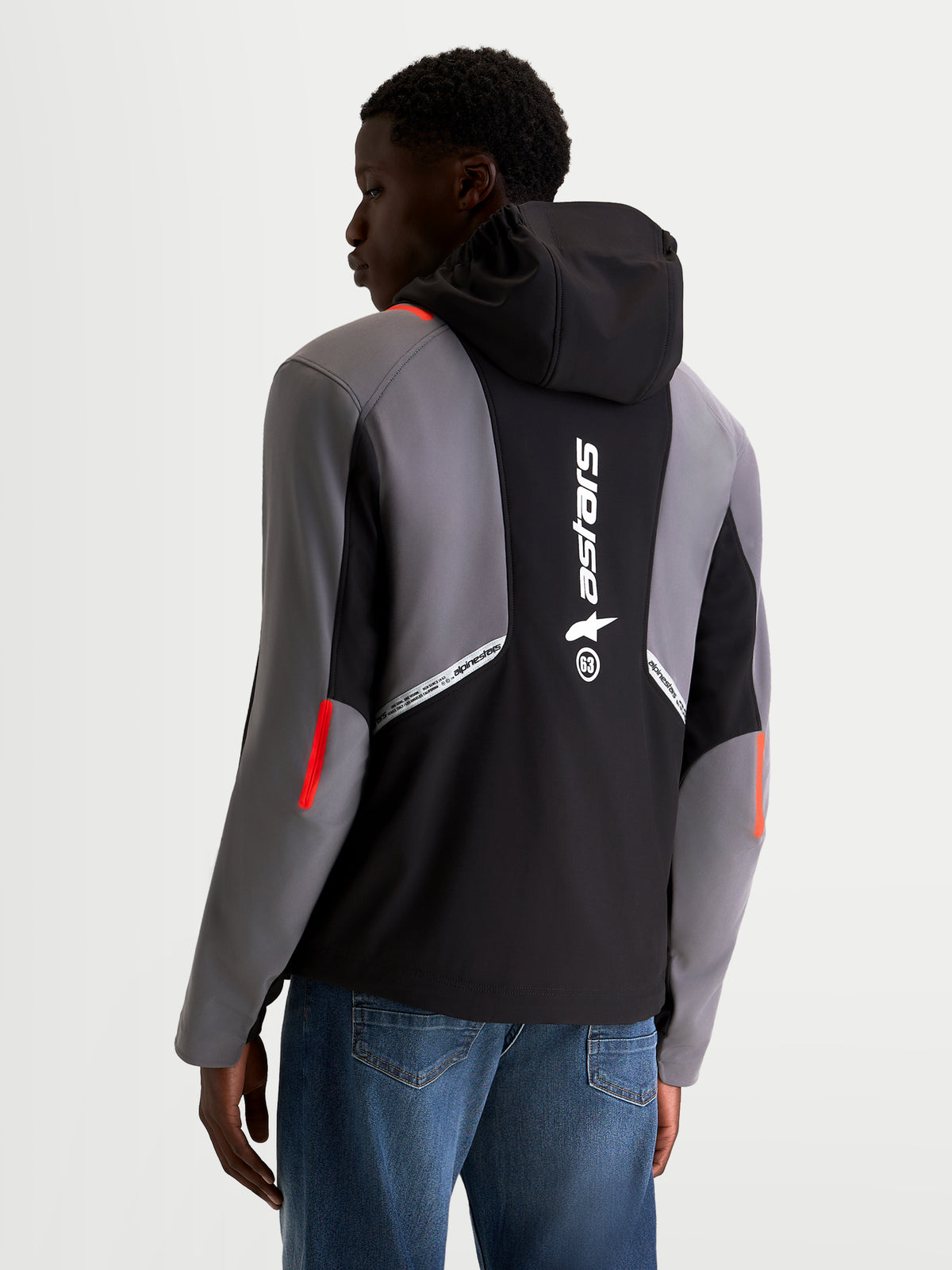 Alpinestars C-5 Drystar Kurtka, męska miejska kurtka motocyklowa softshell, czarna i ciemnoszara, widok z tyłu na modelu przedstawiający zintegrowany kapturem, duże odblaskowe logo Alpinestars na plecach oraz wodoodporną konstrukcję tekstyliów