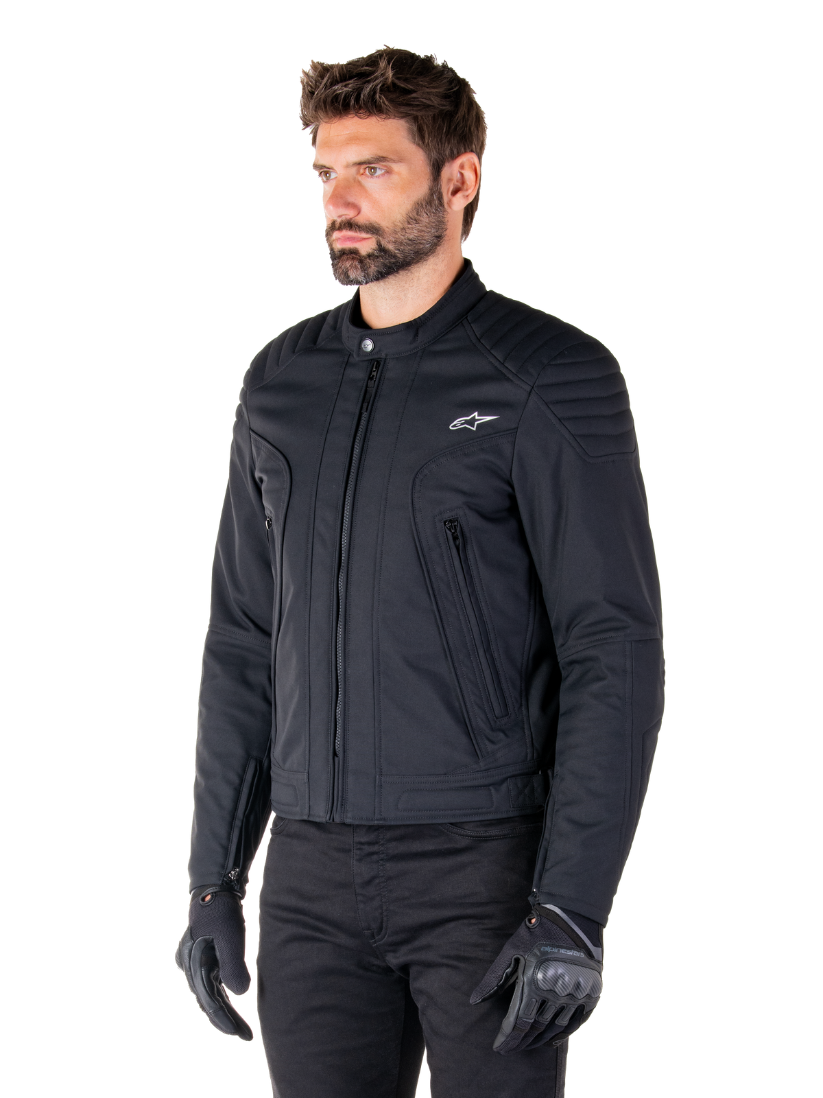 Kurtka Alpinestars Clayton WR, czarna, miejska tekstylna kurtka motocyklowa z pikowanymi detalami na ramionach i przedramionach, dopasowany krój, matowe wykończenie, noszona przez motocyklistę w czarnych rękawicach.