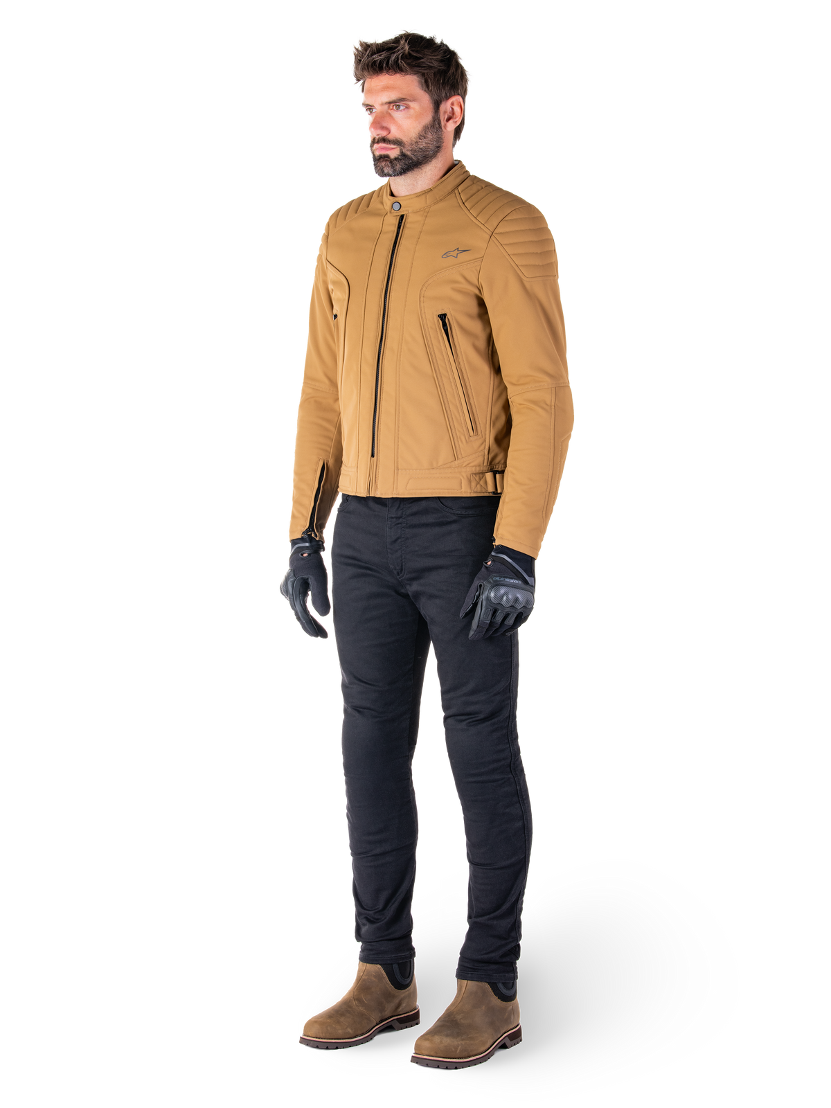 Mężczyzna w kurtce Alpinestars Clayton WR w kolorze Utility Brown Light Gold, współczesna miejska kurtka motocyklowa z pikowanymi detalami na ramionach, stylizowana z czarnymi spodniami, czarnymi rękawicami i brązowymi butami
