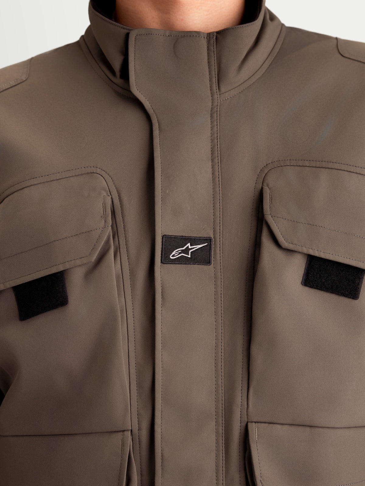 Alpinestars Altan Drystar Kurtka, męska współczesna kurtka motoryzacyjna w kolorze brązowym orzechowym, zbliżenie pokazujące konstrukcję z poliestru, podwójne kieszenie cargo oraz zintegrowany ciepły kołnierz