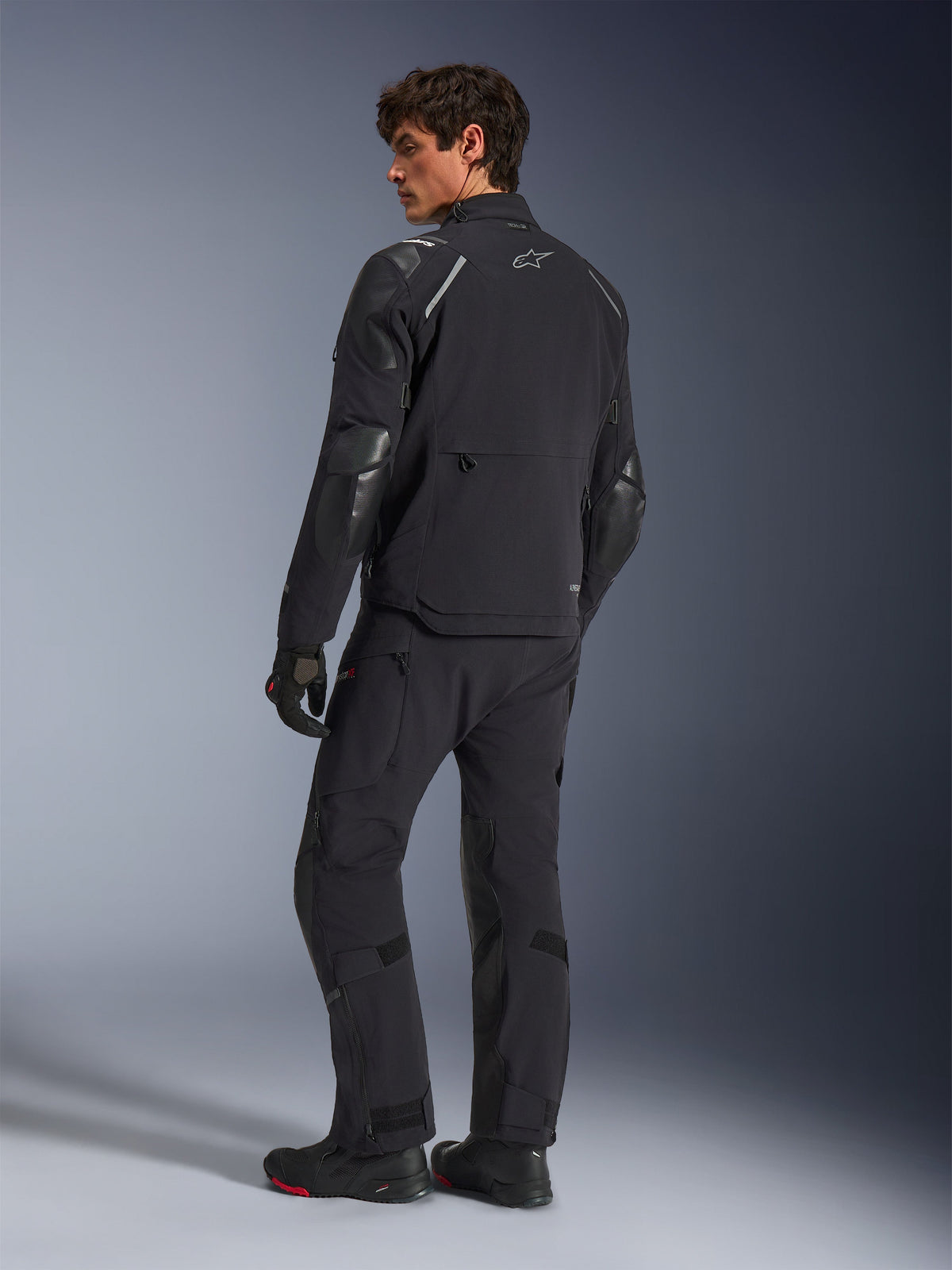 Kurtka Alpinestars Andes Pro Drystar® XF, motocyklowa kurtka adventure, czarna, widok z tyłu w zestawie z pasującymi spodniami i butami, ze wzmocnionymi panelami i srebrnym logo gwiazdy, techniczna odzież motocyklowa na każdą pogodę