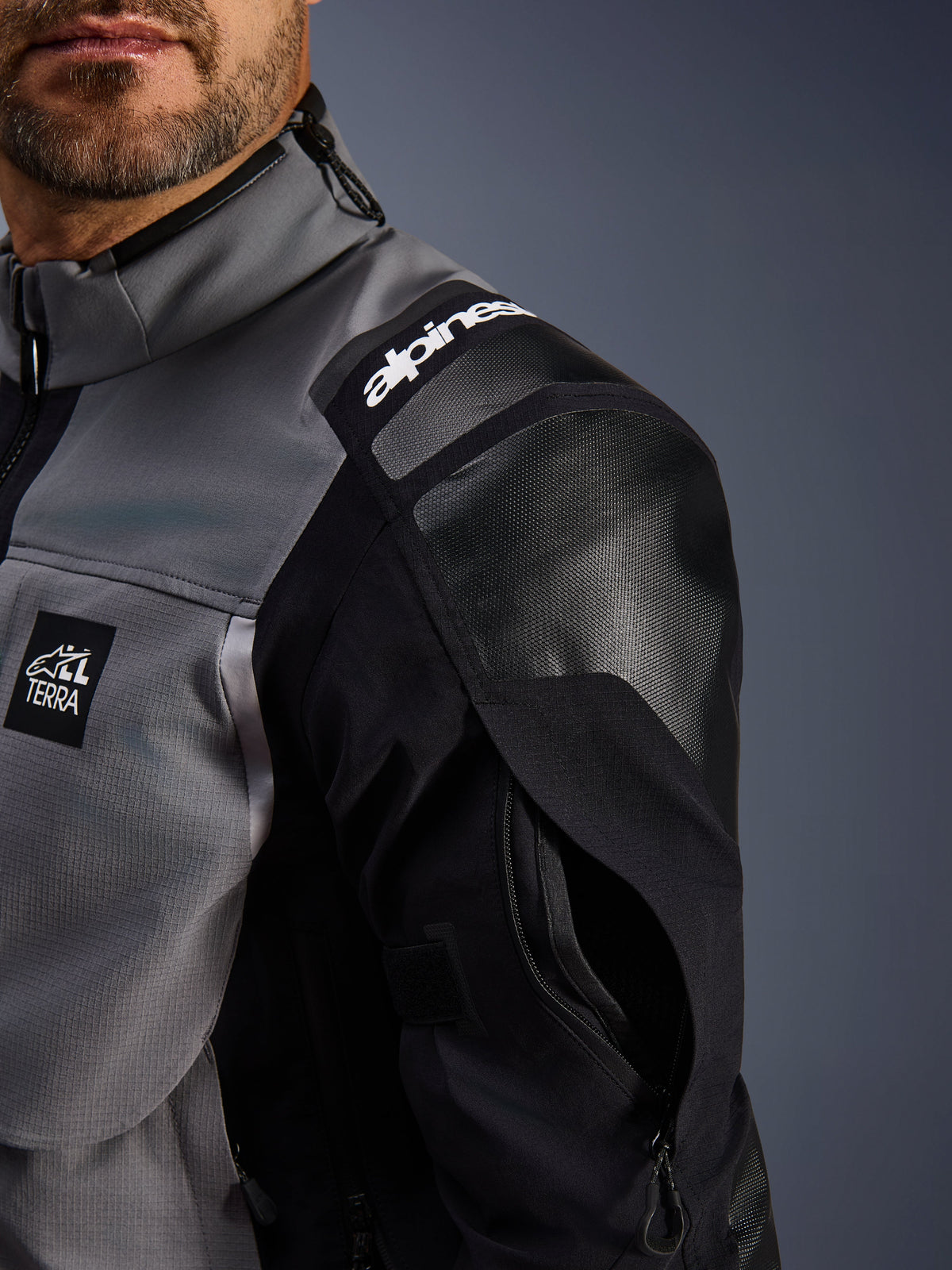 Alpinestars Andes Pro Drystar® XF Jacket, Adventure Motorcycle Jacket, Dark Gray and Black, close-up view of reinforced shoulder with Alpinestars branding, 'TERRA' logo patch, and zippered sleeve ventilation on technical textile shell.