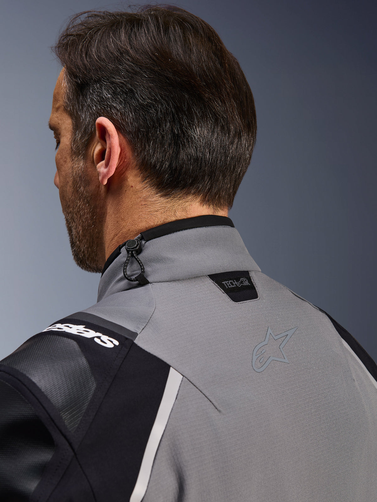Alpinestars Andes Pro Drystar® XF Jacket, Dark Gray and Black, close-up of the back collar and upper shoulder, showing the Tech-Air® Ready logo, shock cord adjustment, and tonal Alpinestars star logo on technical textile