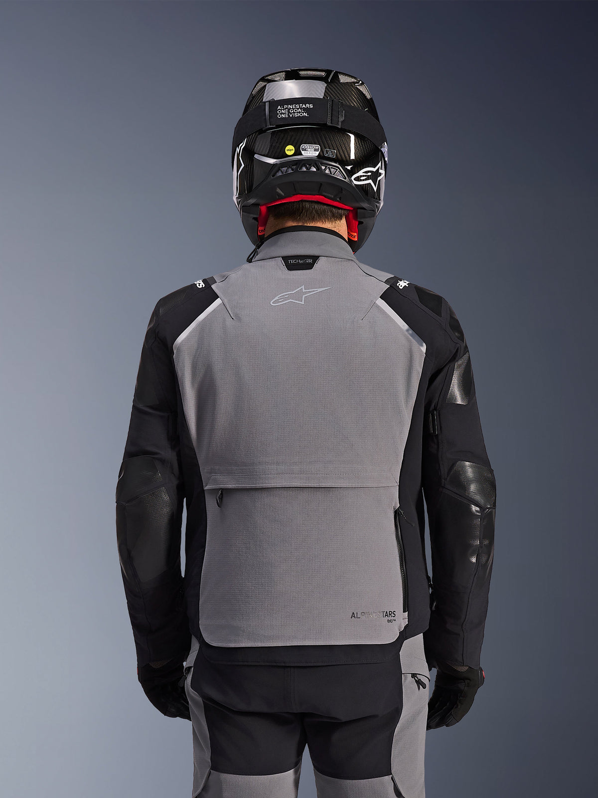 Alpinestars Andes Pro Drystar® XF Jacket, Dark Gray and Black, back view showing large rear storage pocket and Tech-Air branding, worn by a rider with a black helmet and matching riding pants, professional adventure touring gear
