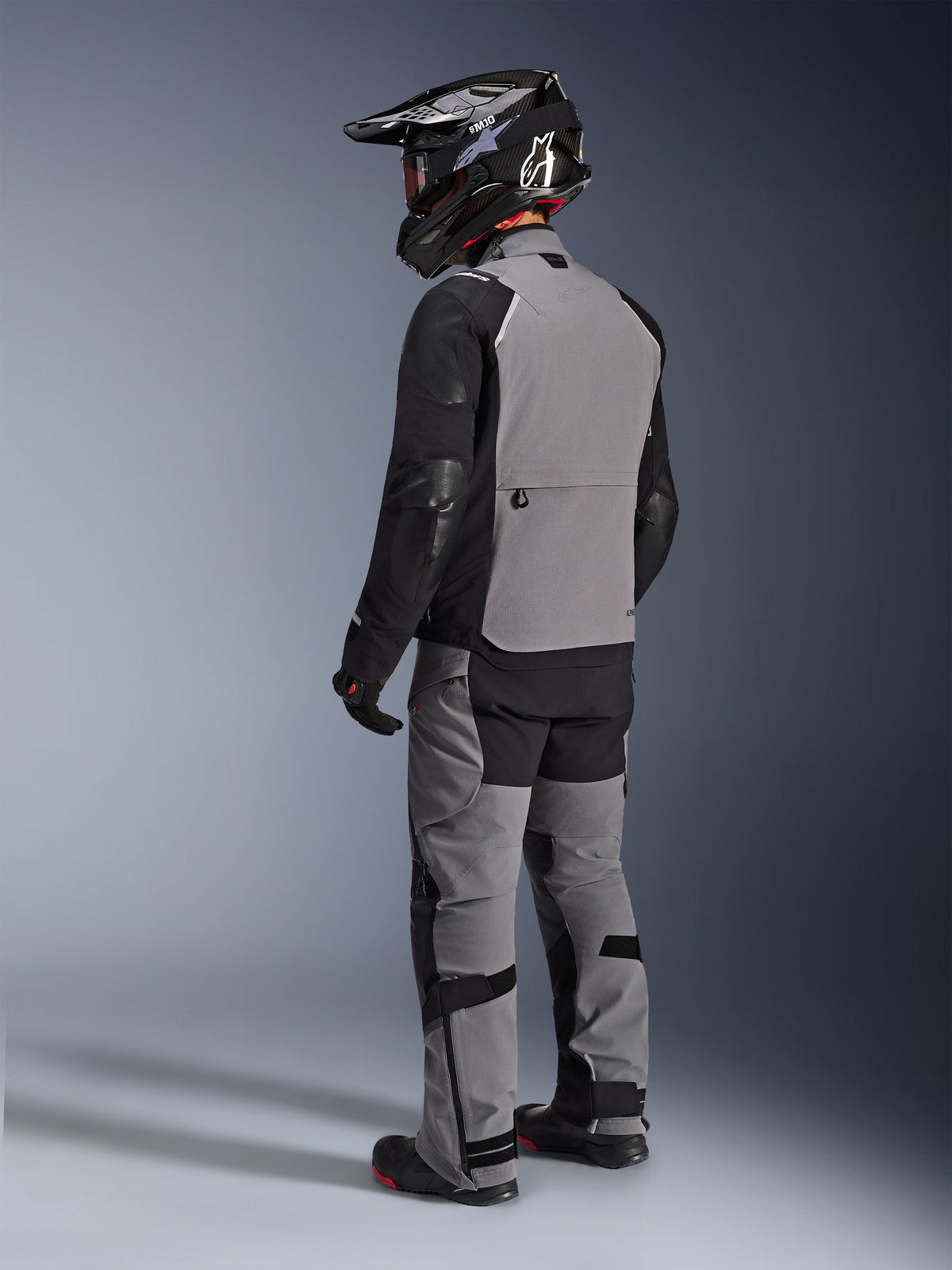 Alpinestars Andes Pro Drystar® XF Jacket, Adventure Motorcycle Jacket, Dark Gray and Black, rear view showing gray back panel and black sleeves, worn with matching pants and black helmet, technical all-weather riding gear
