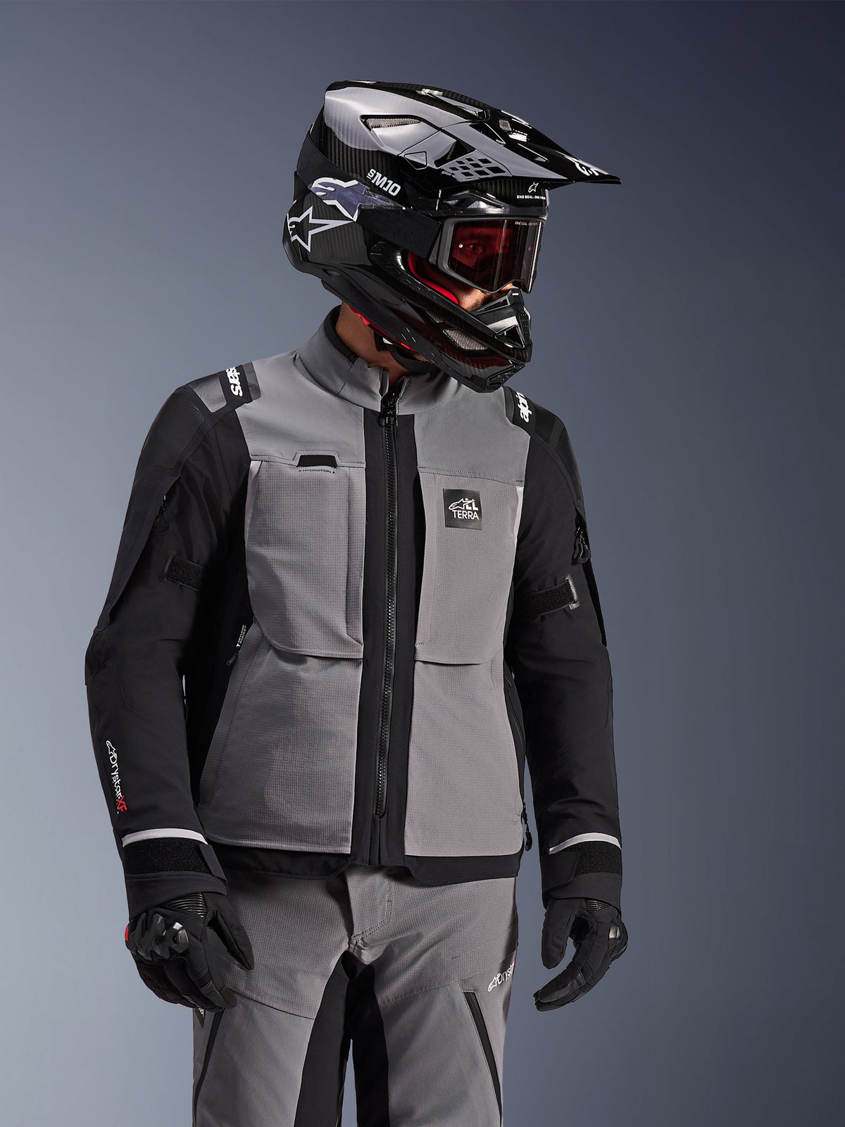 Alpinestars Andes Pro Drystar® XF Jacket, Dark Gray and Black, adventure motorcycle jacket worn with black SM10 helmet and matching riding gear, 3-layer textile design with central zipper and chest pockets, articulated design for all-weather touring