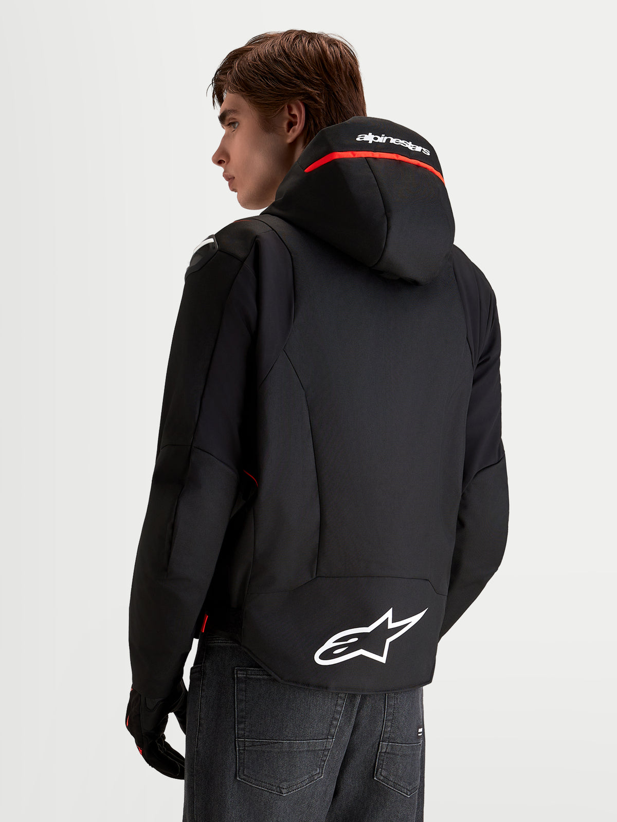Alpinestars Zaca V 2 Waterproof, męska wodoodporna kurtka motocyklowa, czarna i czerwona, zintegrowany kaptur z logo, tył z białym logo Astar, widok z tyłu na modelu.