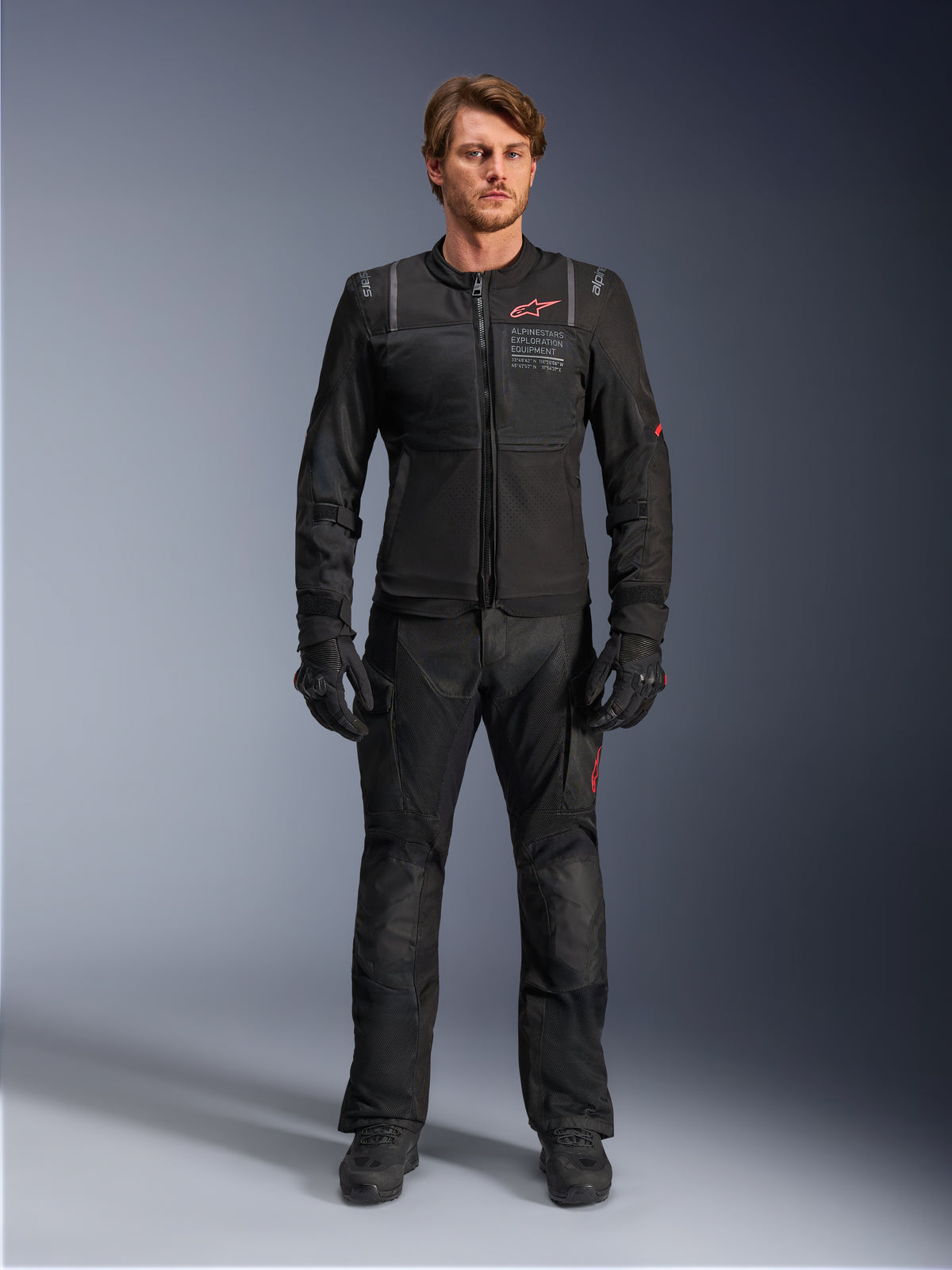 Alpinestars Kurtka ST-2 Air, męska kurtka motocyklowa adventure touring, czarna z czerwonym logo i panelami z siatki, pokazana na modelu w pełnym stroju.