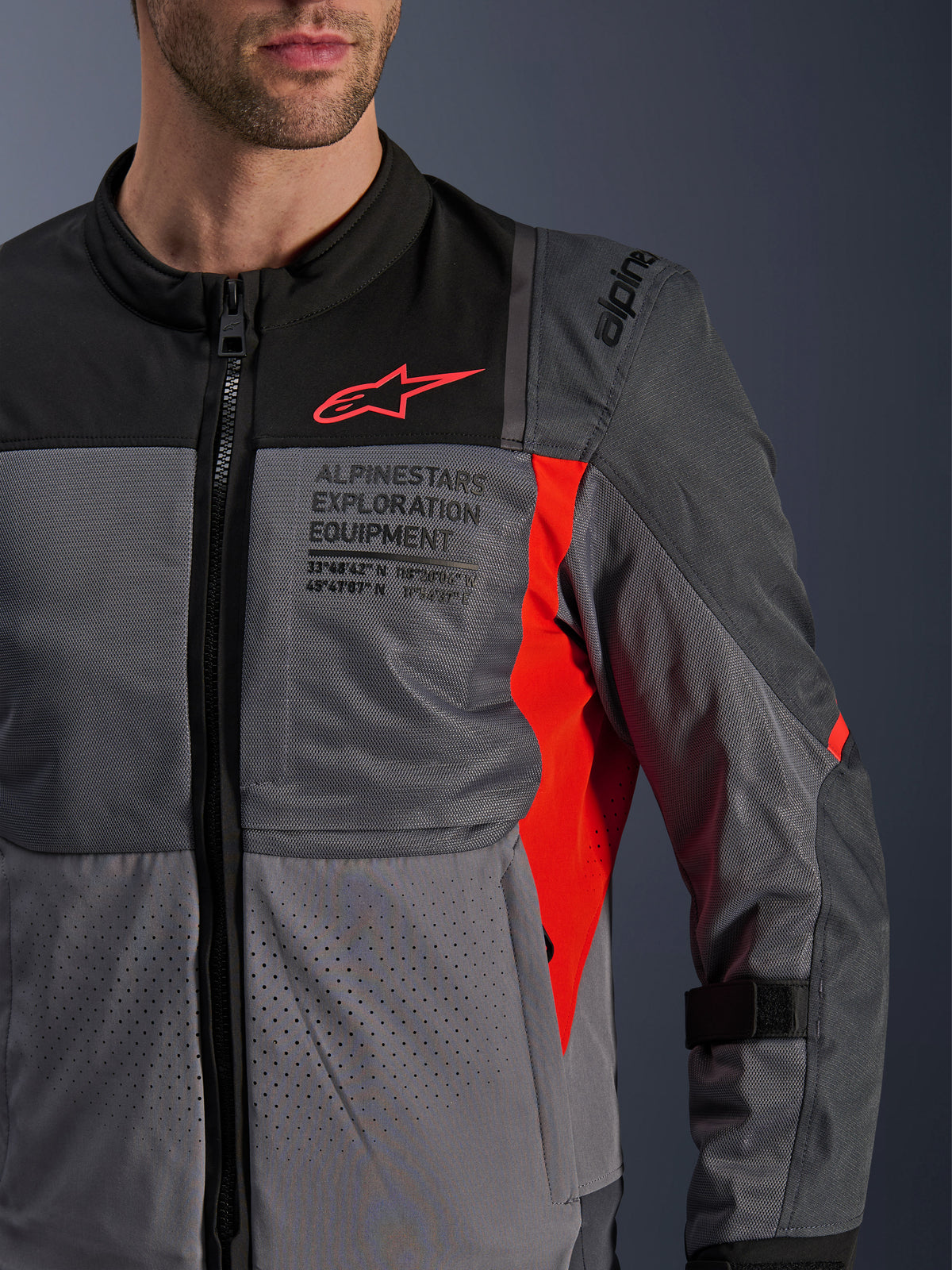 Kurtka Alpinestars ST-2 Air, męska tekstylna kurtka motocyklowa touring, szara i czerwona, oddychające panele z siatki, laserowe perforacje i logo Alpinestars Exploration Equipment.