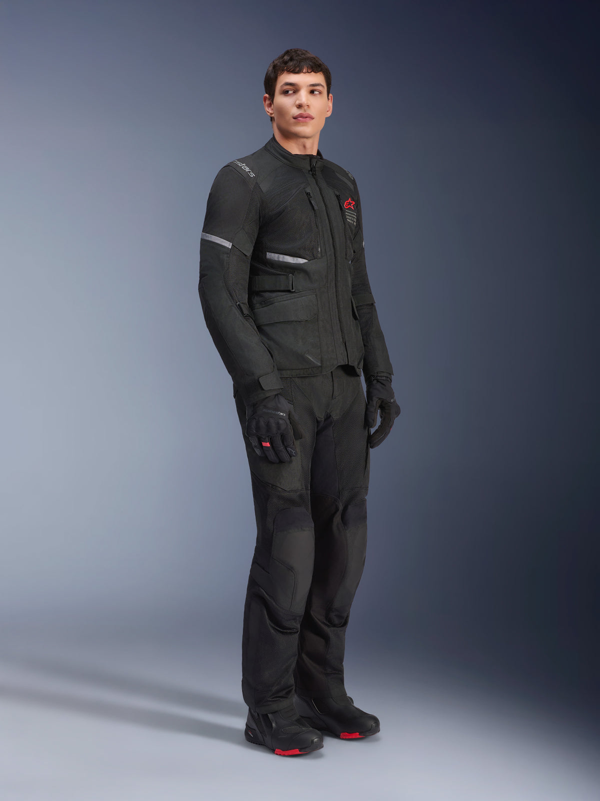 Kurtka i spodnie Alpinestars Andes Air Drystar®, strój turystyczny adventure, czarny, widok na całą sylwetkę modelu w kompletnym zestawie motocyklowym z rękawicami i butami, oddychające panele z siatki i czerwone akcenty z logo