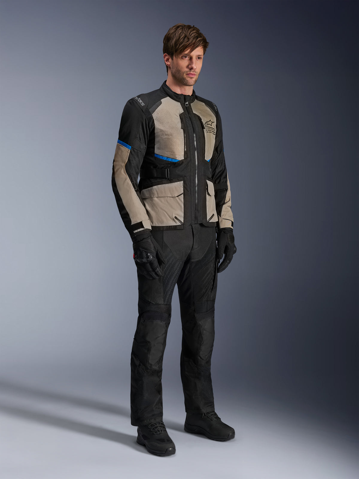 Kurtka Alpinestars Andes Air Drystar®, motocyklowa kurtka turystyczna, czarna z szarymi i jasnoniebieskimi akcentami, noszona z pasującymi spodniami i rękawicami, obszerne panele z siatki dla przepływu powietrza, krój szosowy, odzież adventure touring
