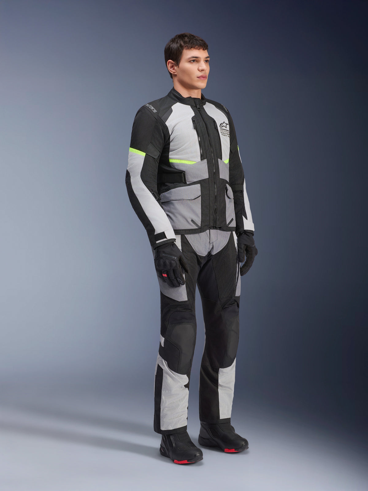 Kurtka i spodnie Alpinestars Andes Air Drystar®, odzież motocyklowa adventure touring, kolor Ice Gray, Dark Gray i czarny z neonowożółtymi akcentami, zestawione z czarnymi rękawicami i butami, zdjęcie studyjne całej sylwetki, odzież turystyczna na dwie pory roku